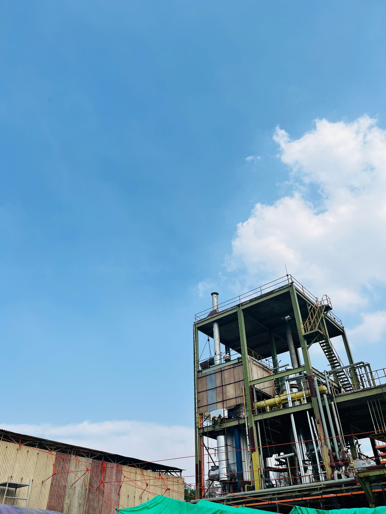 A steel framed process plant with pipework and stair towers under a clear sky