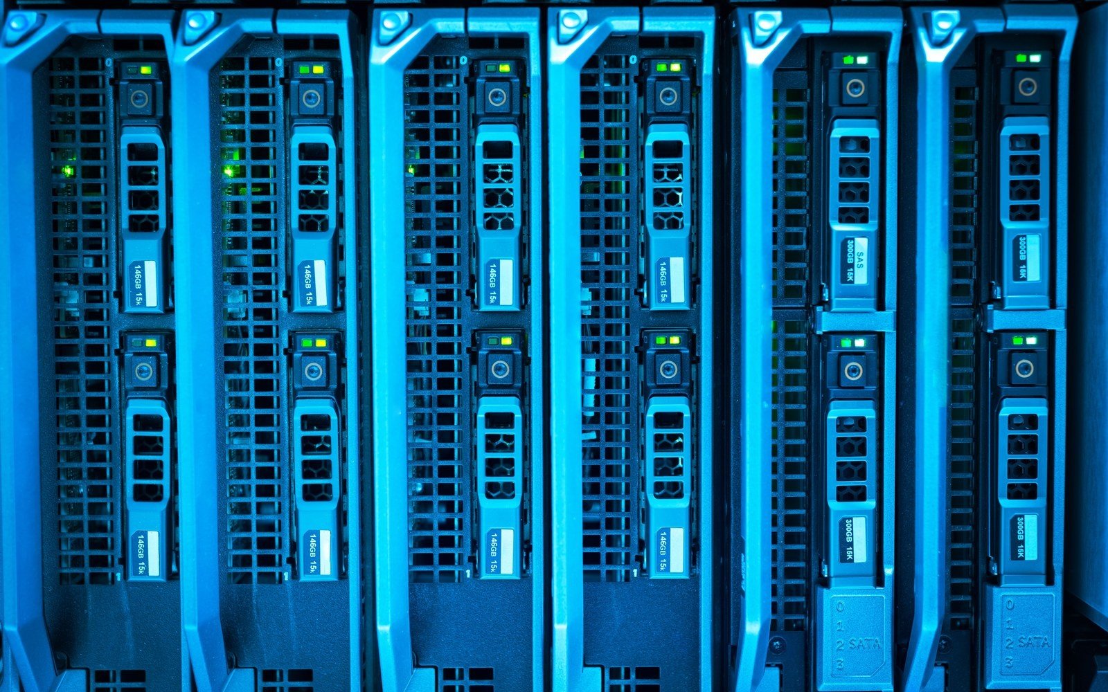 A close view of server blades stacked in a rack, drive caddies and ventilation grilles lit blue with small green and amber status lights