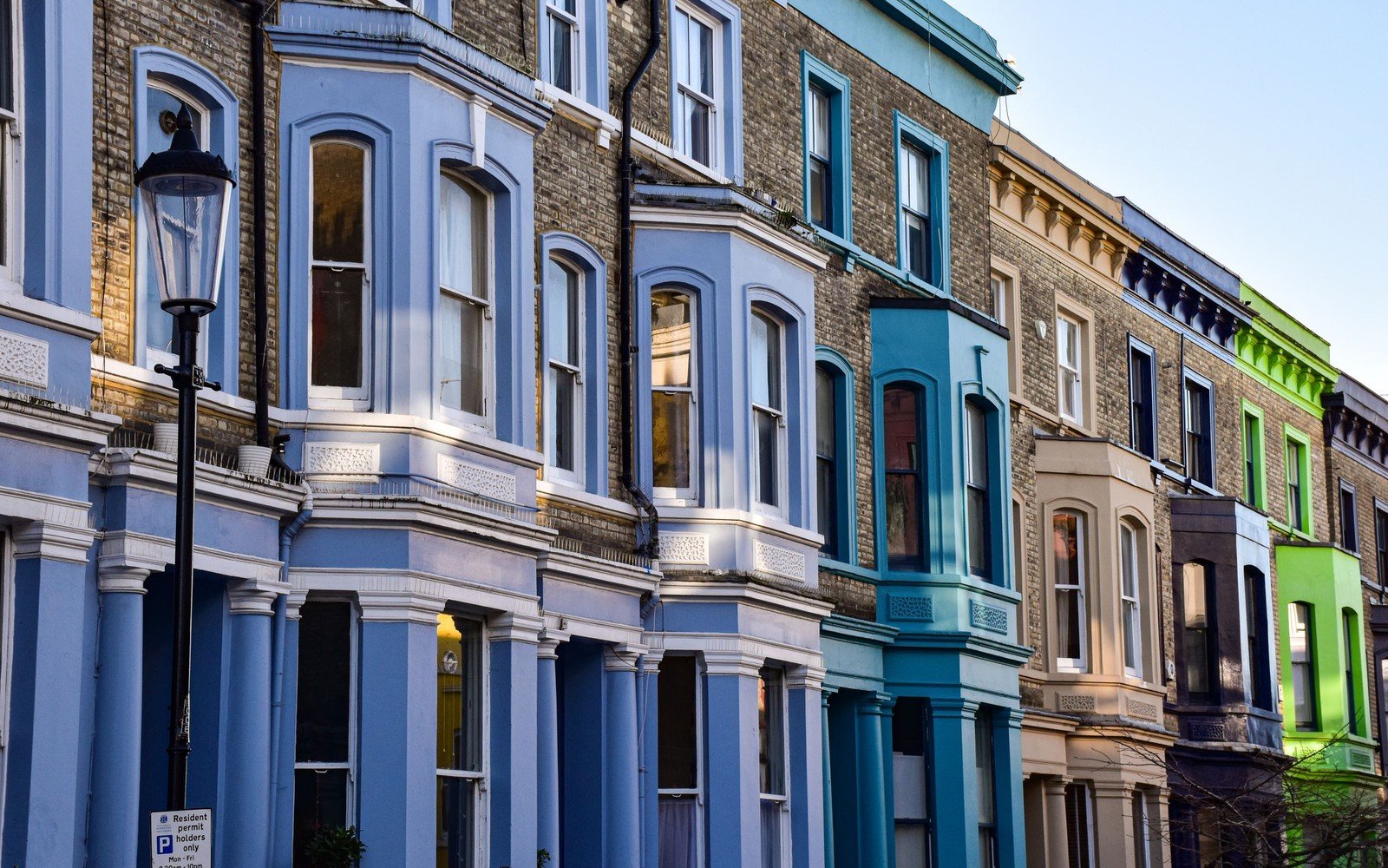 A row of painted Victorian terraced houses with bay windows and a cast iron street lamp in London