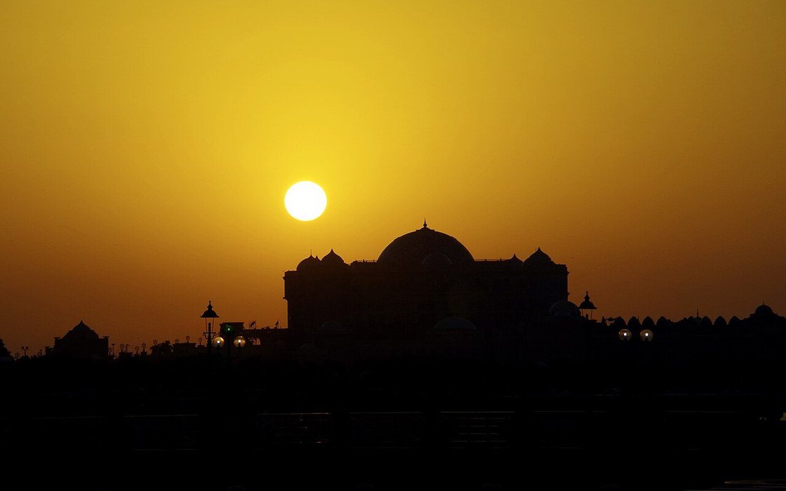 A domed building silhouetted against the setting sun in Abu Dhabi
