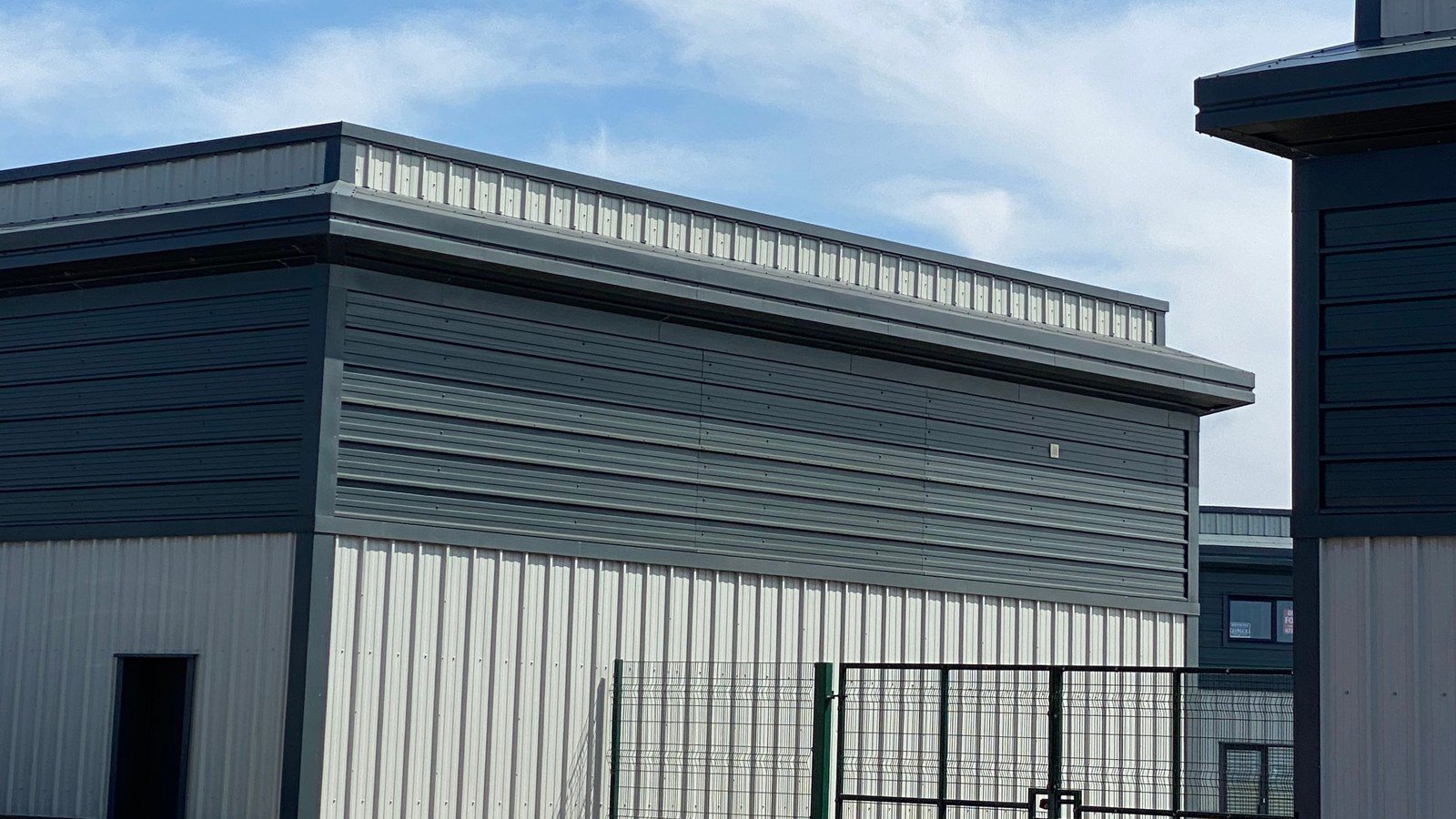 A modern light industrial unit behind a palisade fence, location not identified
