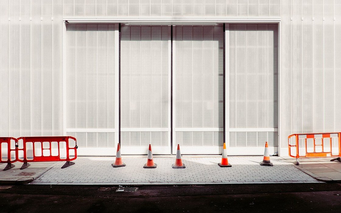 Traffic cones and barriers in front of a hoarded building facade