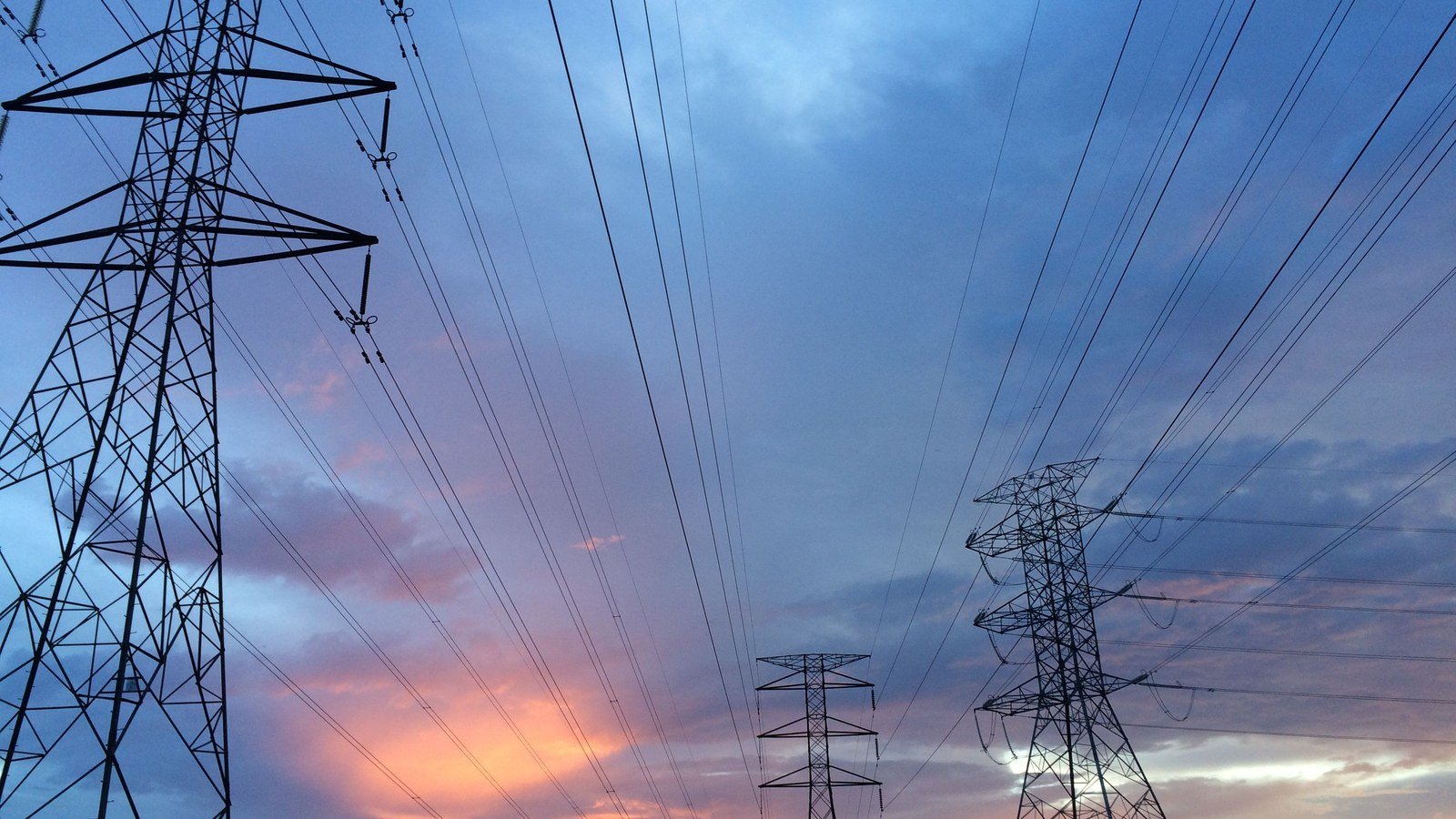 High voltage transmission towers and conductors against an evening sky