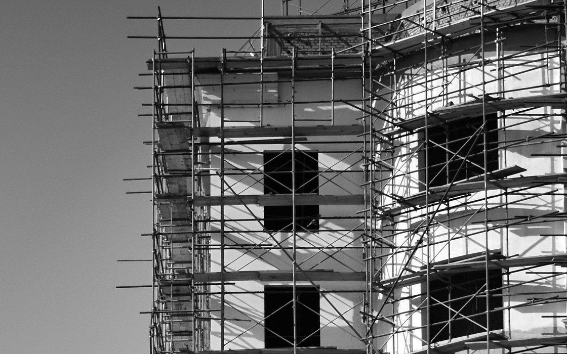 A tube and fitting scaffold with boarded working lifts and facade bracing erected against the elevation of a multi storey building