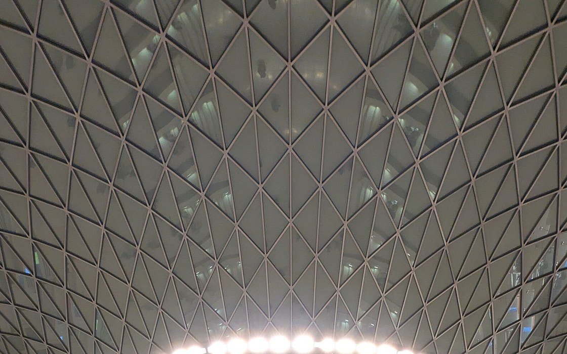 A triangulated glazed roof converging above the lit rim of a circular stone drum