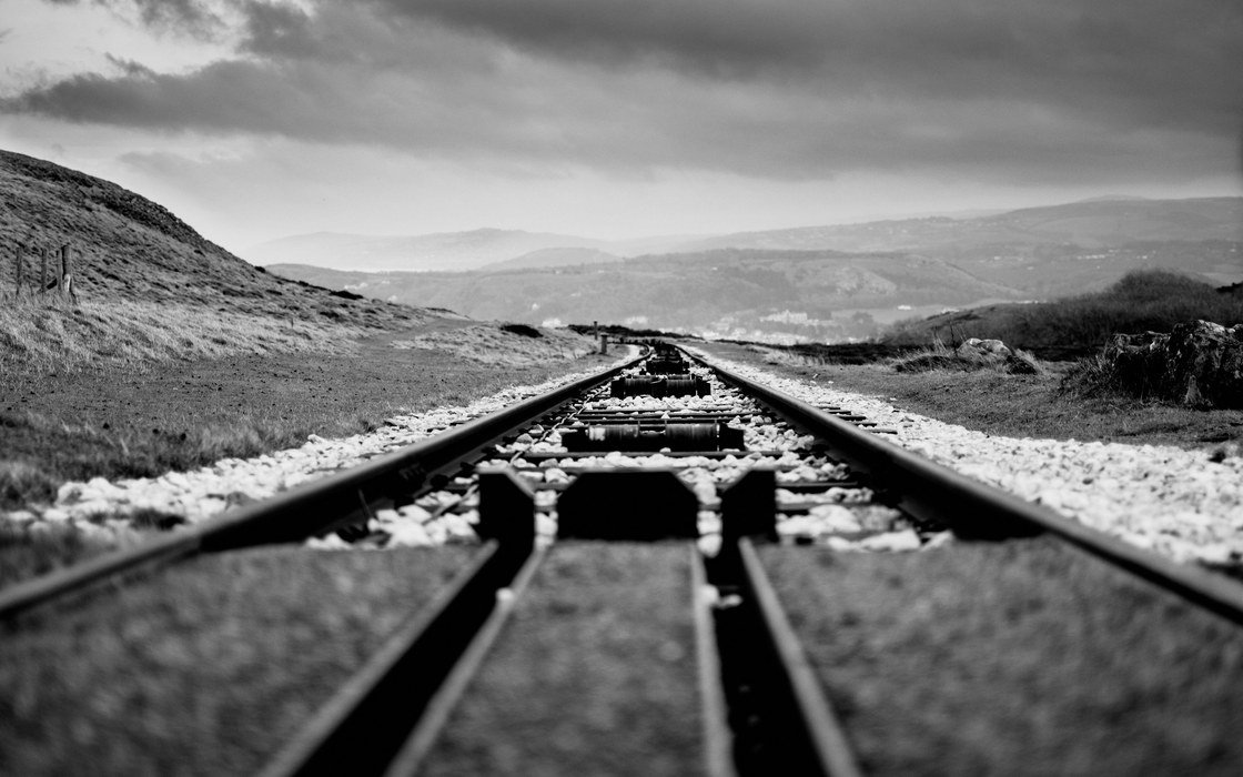 Railway track running away across open hill ground under a heavy sky