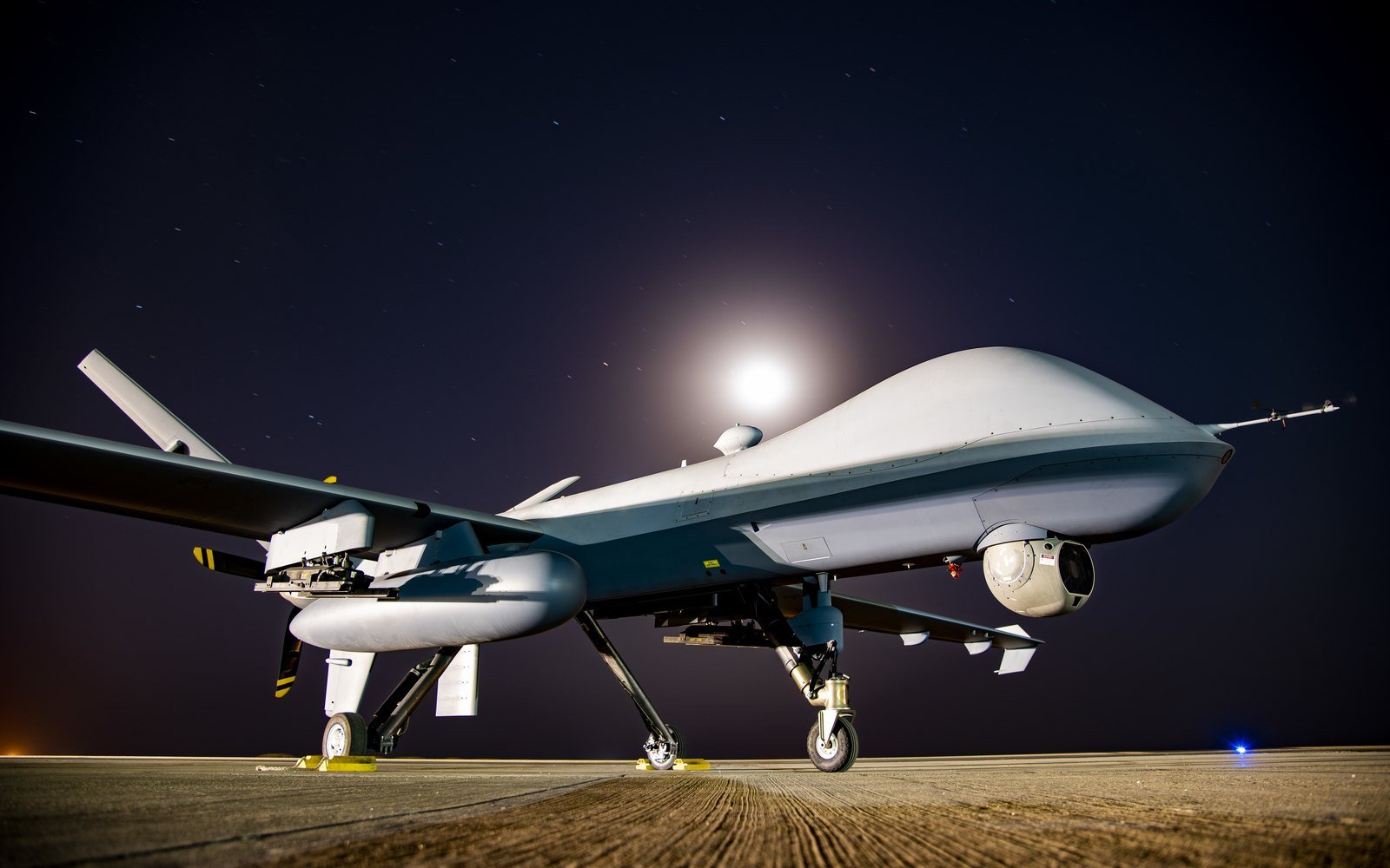 An armed uncrewed aircraft on a flight line at night
