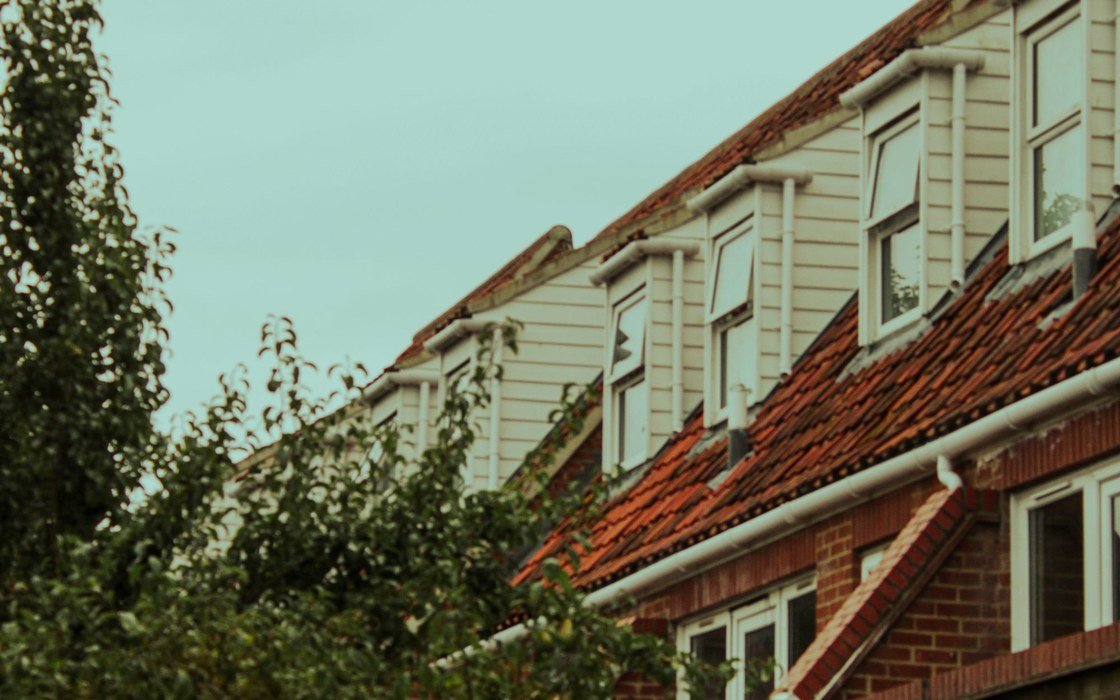 A row of terraced houses with clay tiled roofs, dormer windows and plastic rainwater goods