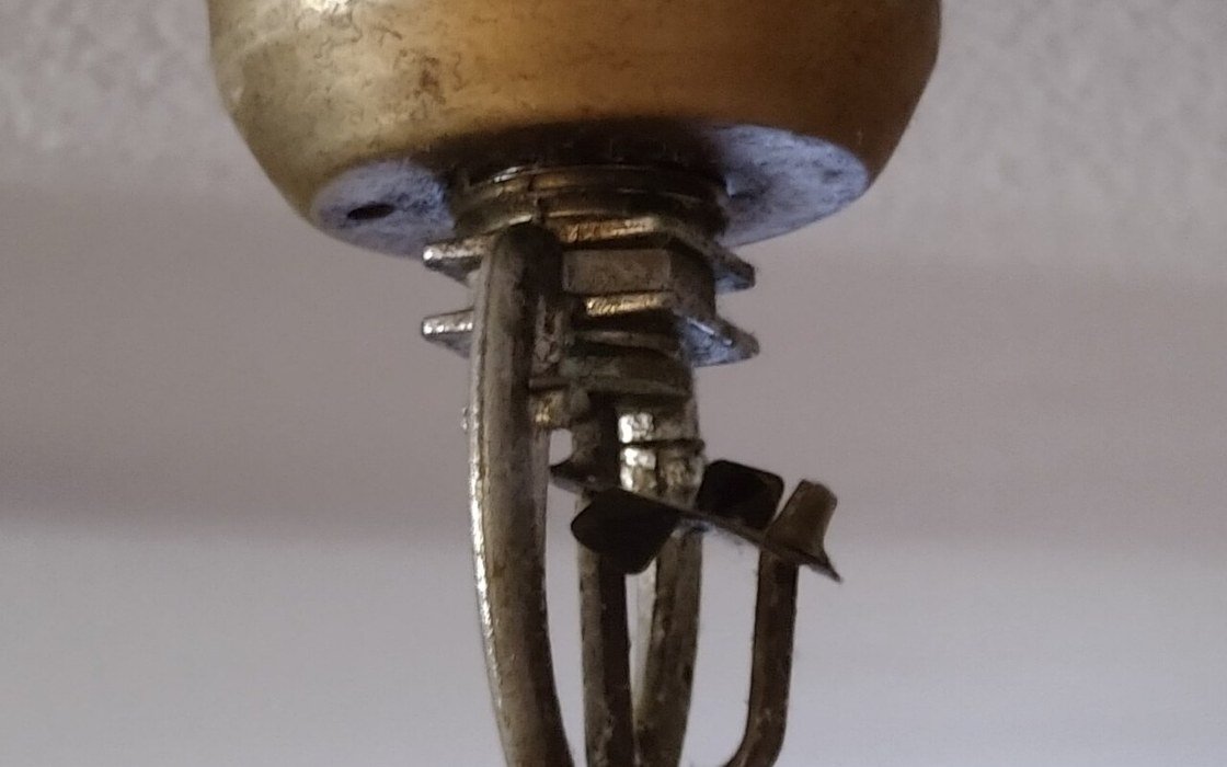 Close-up of a brass fusible link fire sprinkler head fixed to a ceiling