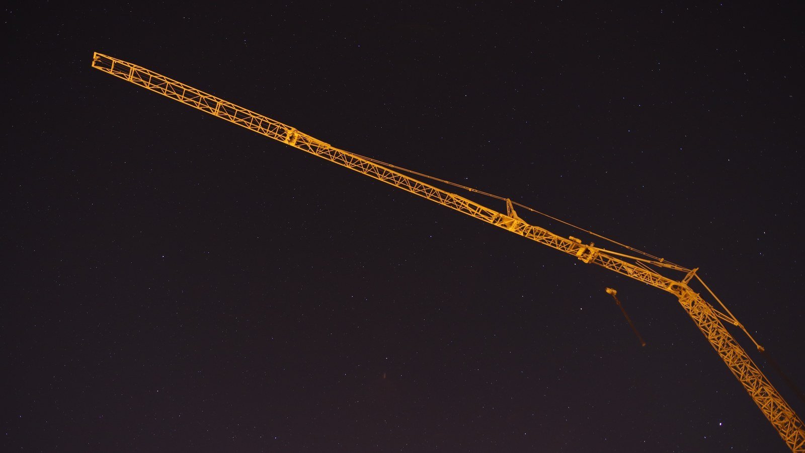 The jib of a tower crane lit against a dark night sky