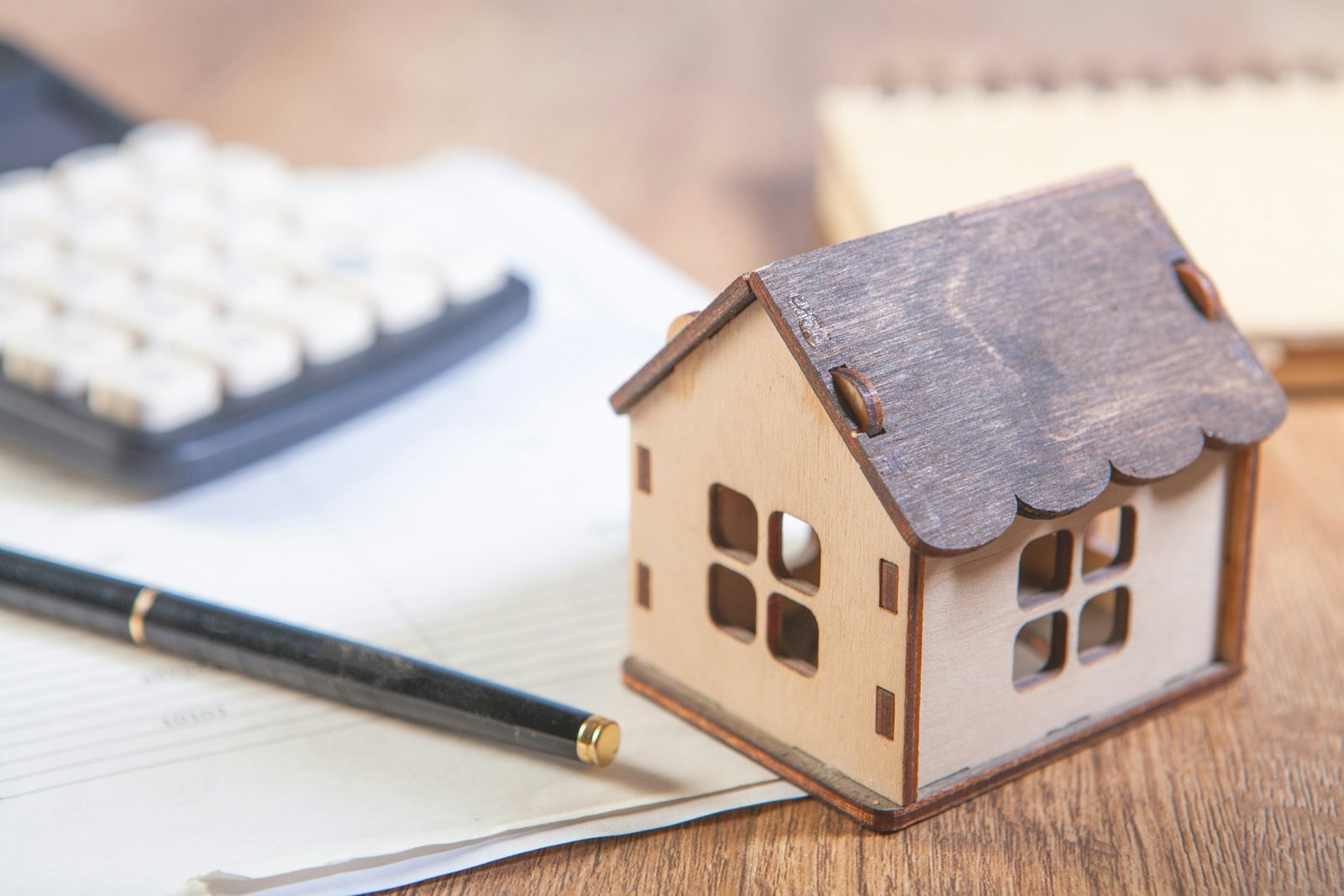 Model home, calculator, notebook and pen arranged for household budgeting