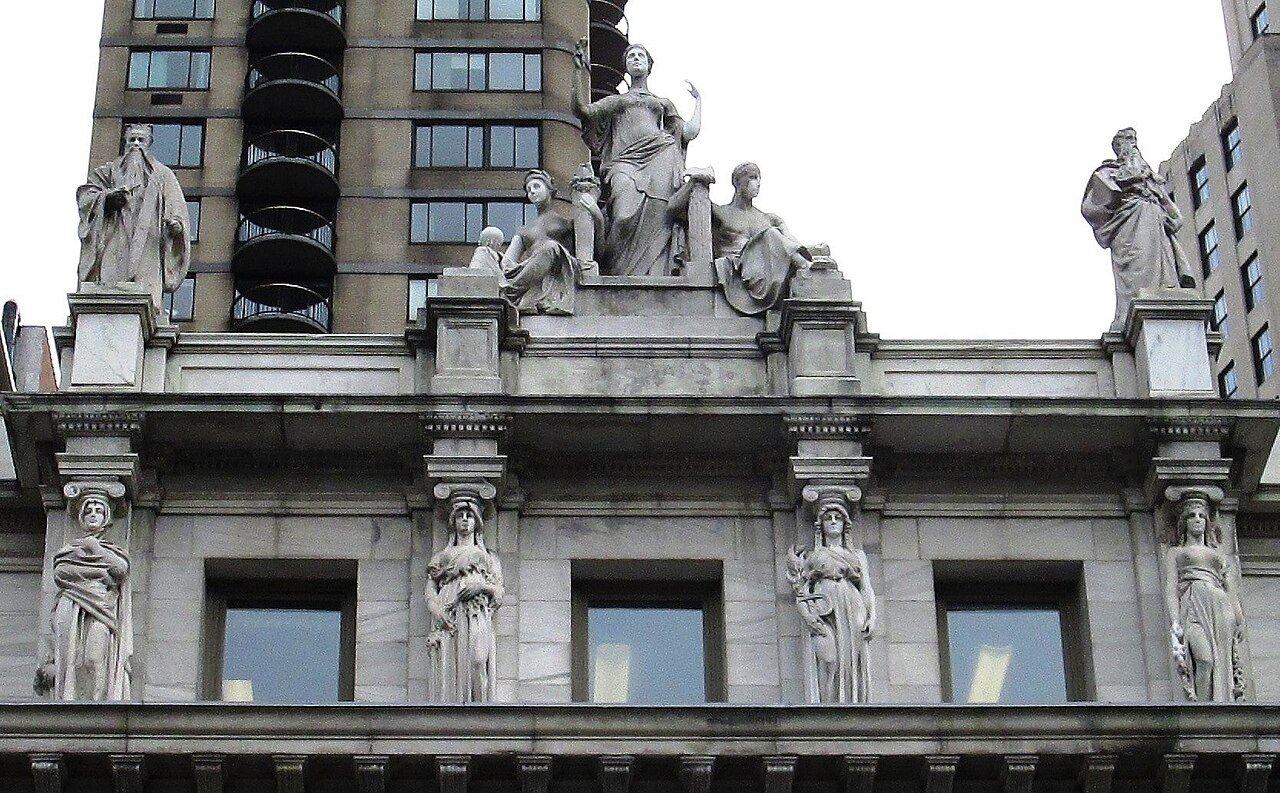 Carved figures and caryatids along the cornice of a classical courthouse facade