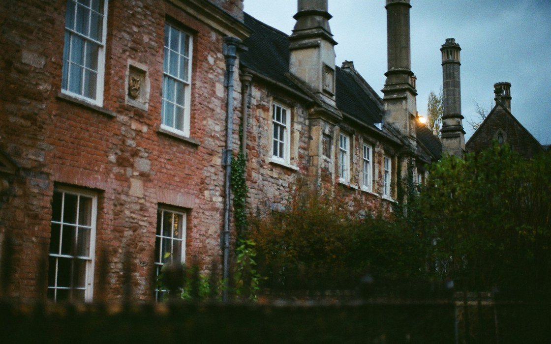 A terrace of old brick buildings with tall chimneys and stone mullioned windows