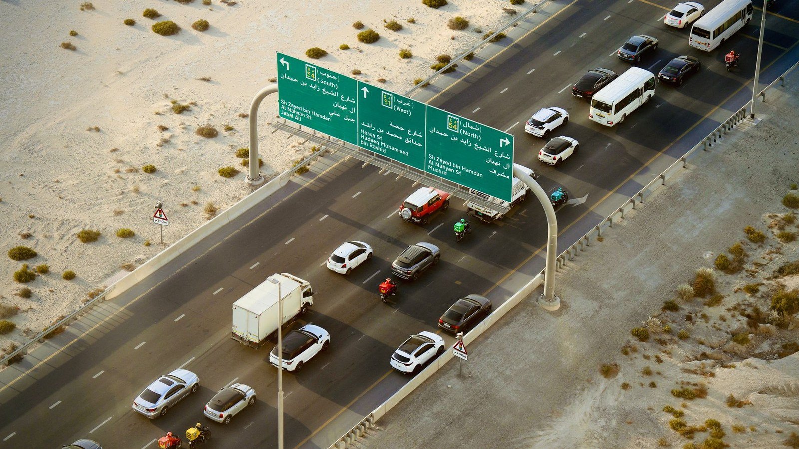 Traffic on Sheikh Zayed bin Hamdan Al Nahyan Street in Dubai, beneath gantry signs for Jebel Ali