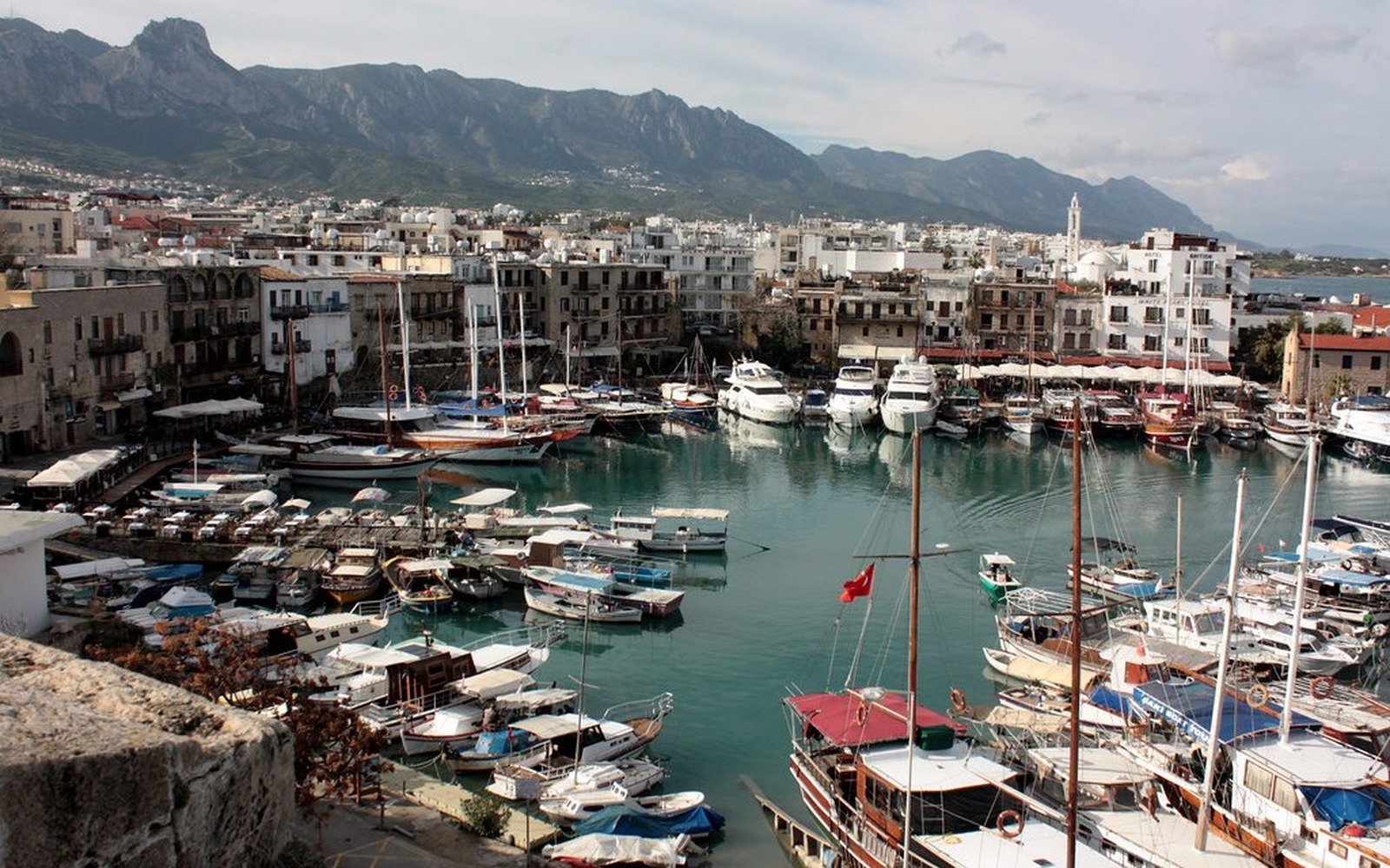 Fishing boats and gulets moored in the harbour at Kyrenia, with the town and the mountains behind