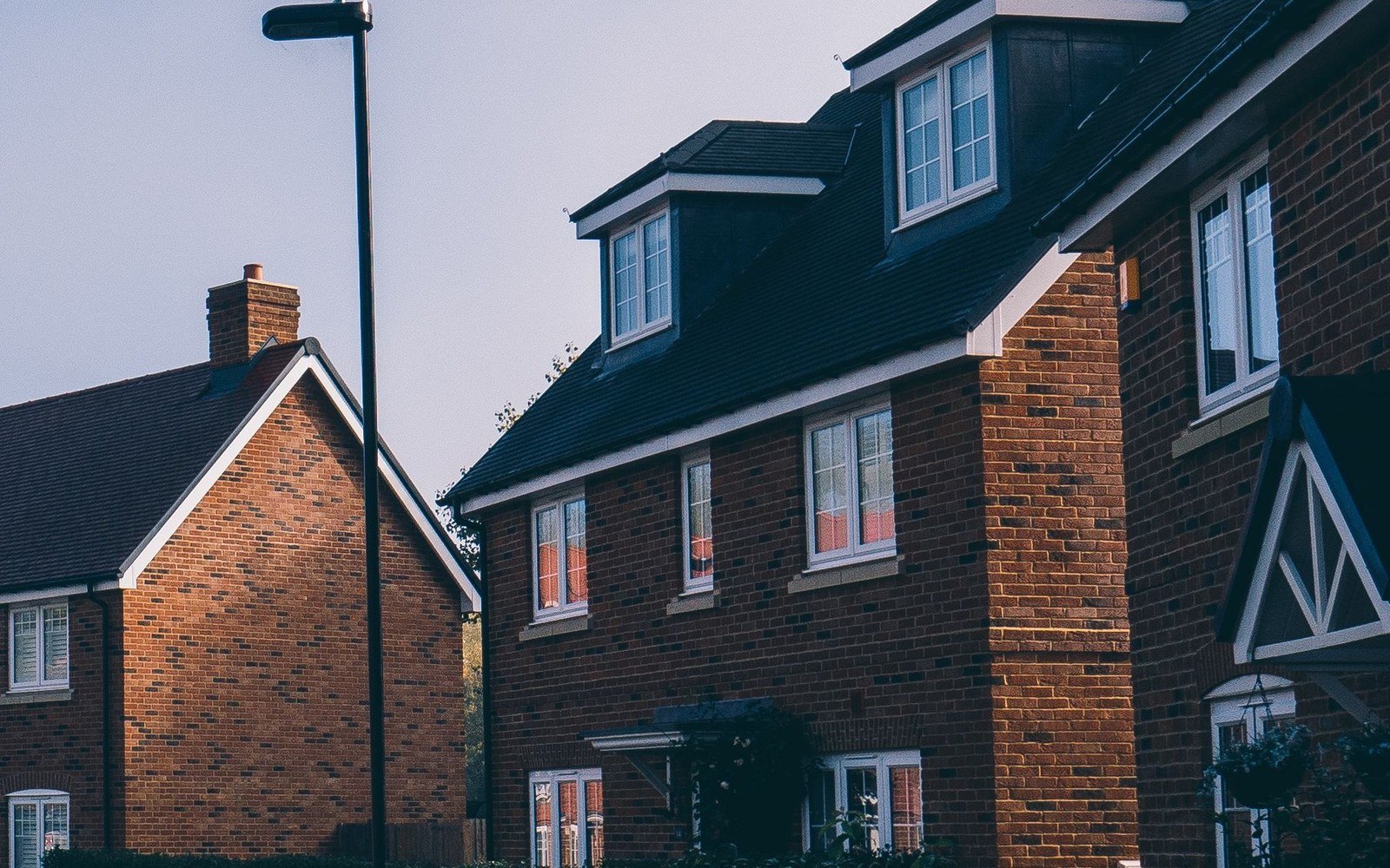 Modern red brick houses on a new residential street in an English town, with a street light and clipped hedges