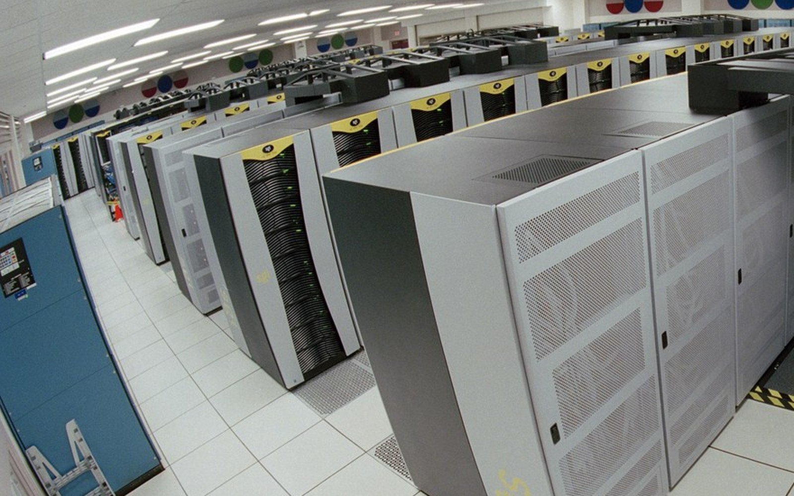 Ranks of tall computing cabinets standing in rows on a raised floor inside a machine hall