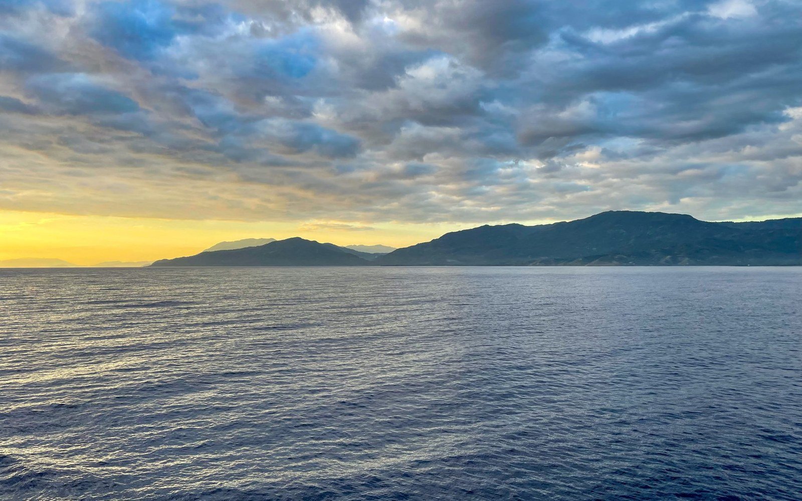 Mountain ridges rising beyond open water at first light in Haiti