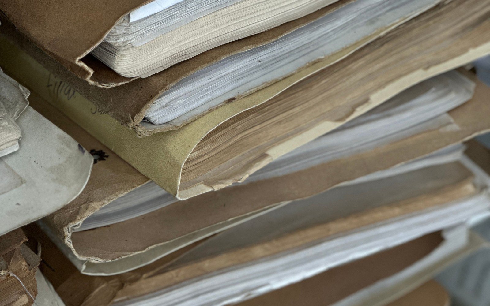 Stacks of worn paper files held in brown card folders