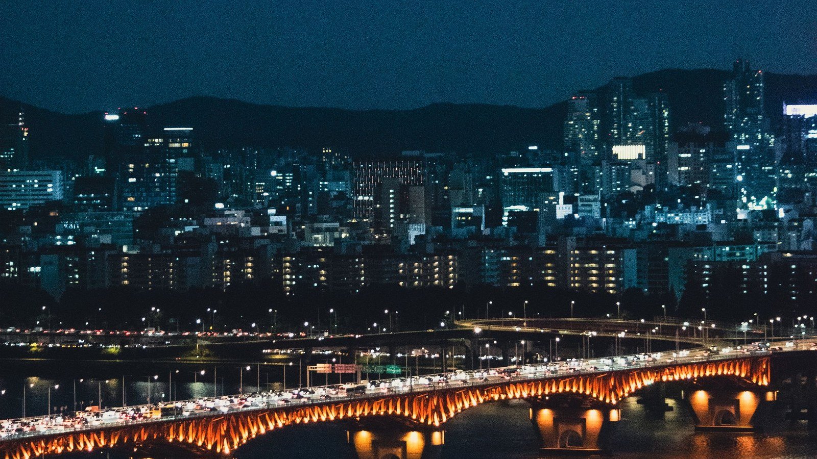 A bridge over the Han river and the Seoul skyline at night