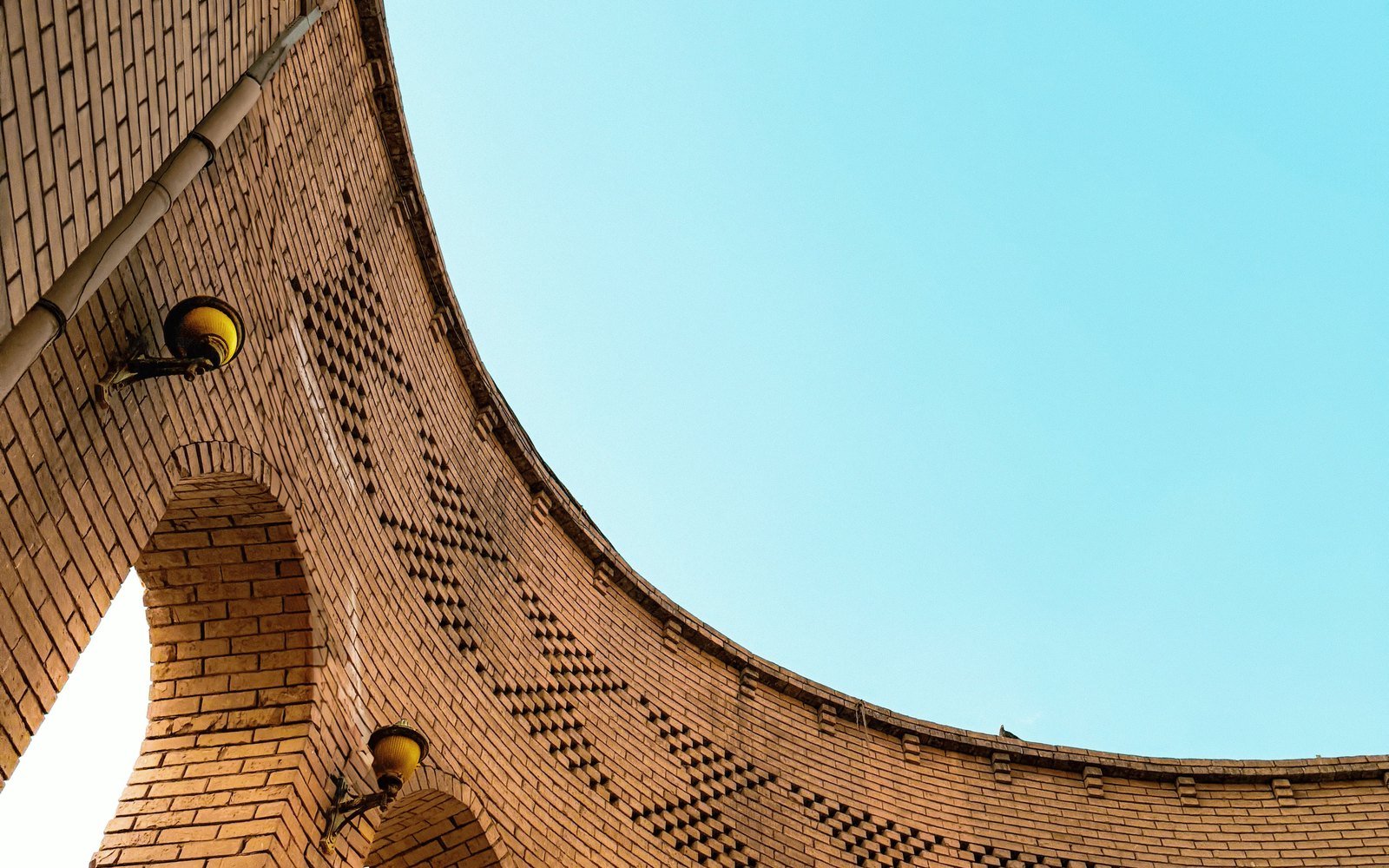 The curved brick wall and arches of the citadel at Erbil seen from below against a clear sky