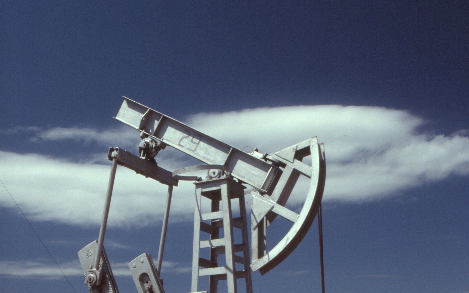 A steel pumpjack at a wellhead against a clear sky