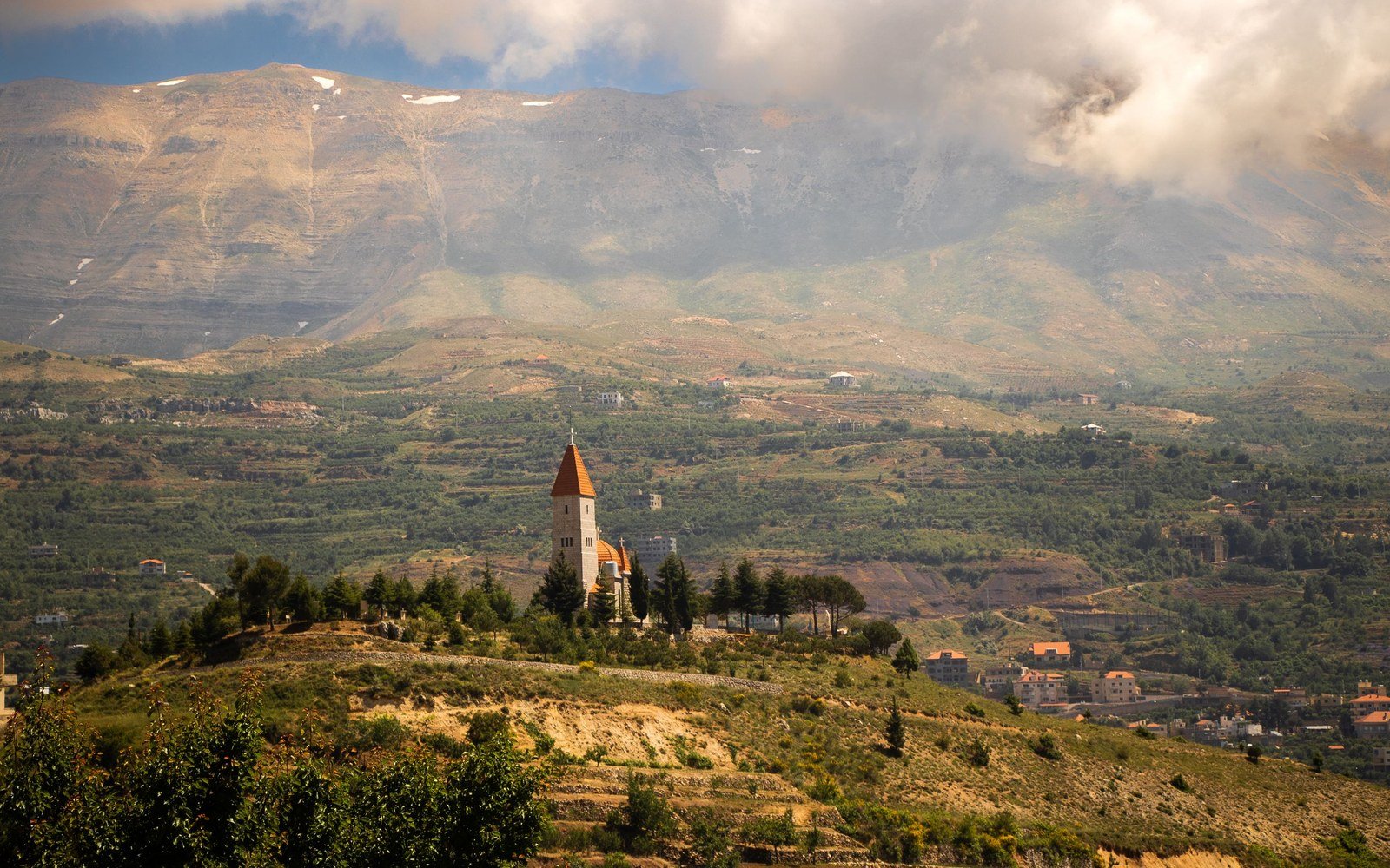 A terraced hillside with scattered houses below a mountain ridge in Lebanon