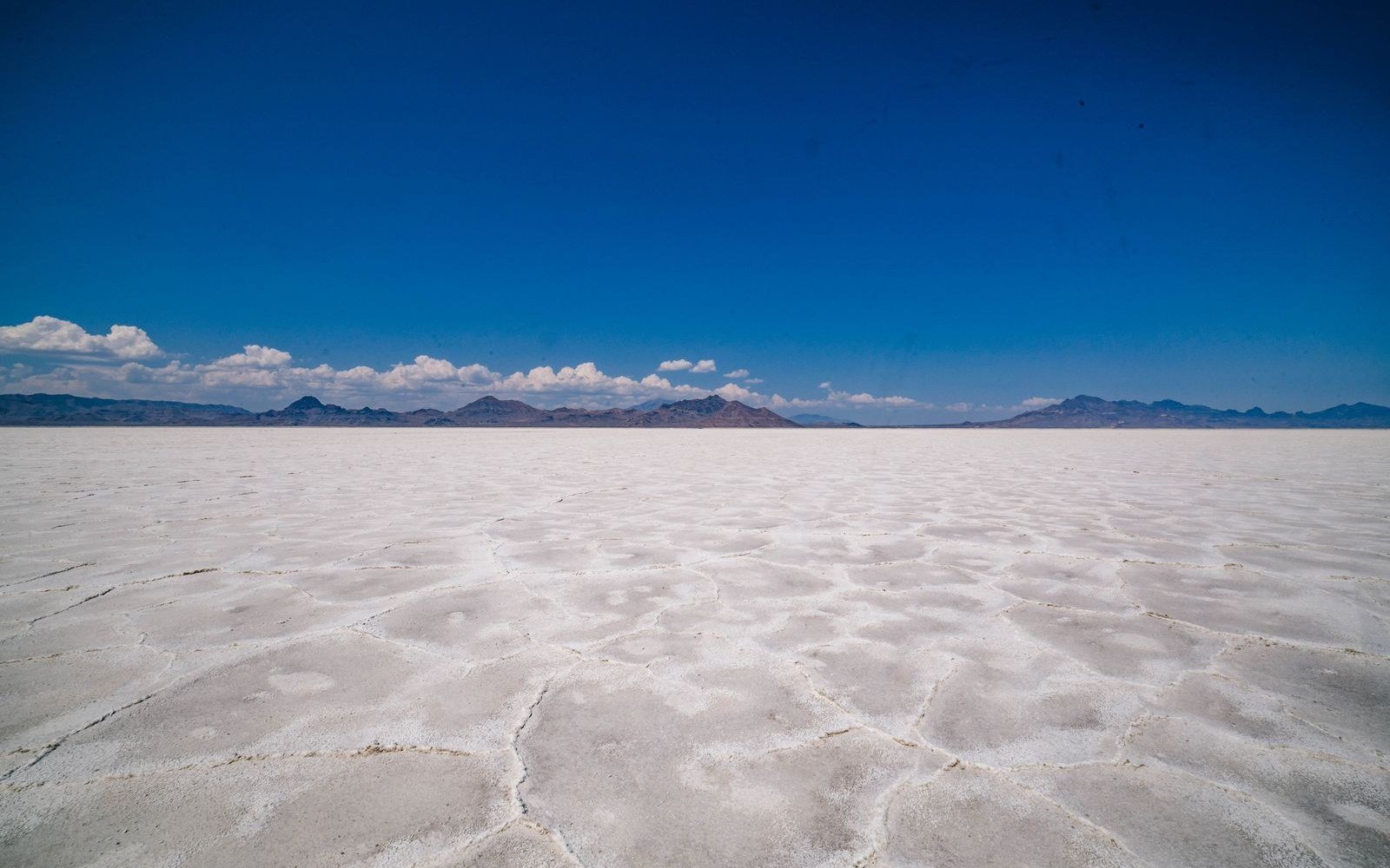 Vast white salt crust of the Bonneville Salt Flats stretching to distant mountains under a deep blue sky