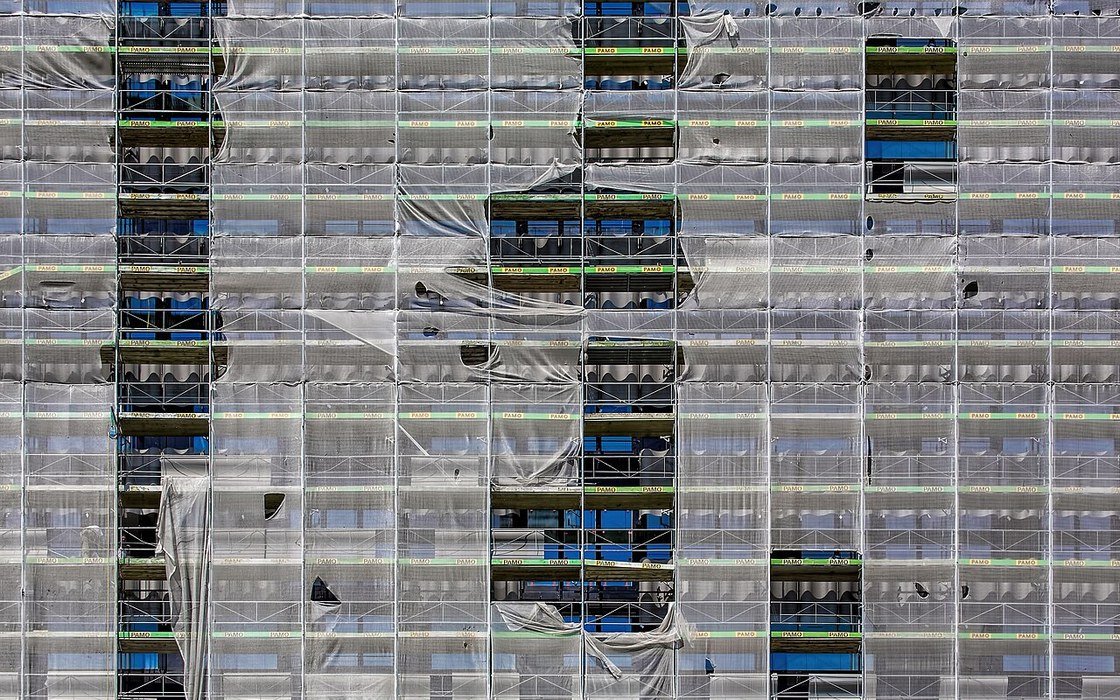 A building wrapped in scaffolding and protective sheeting