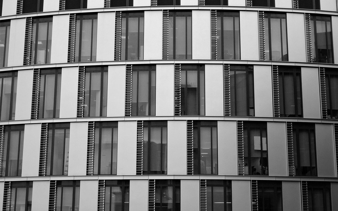 A curved office building elevation of banded glazing and pale cladding, seen straight on