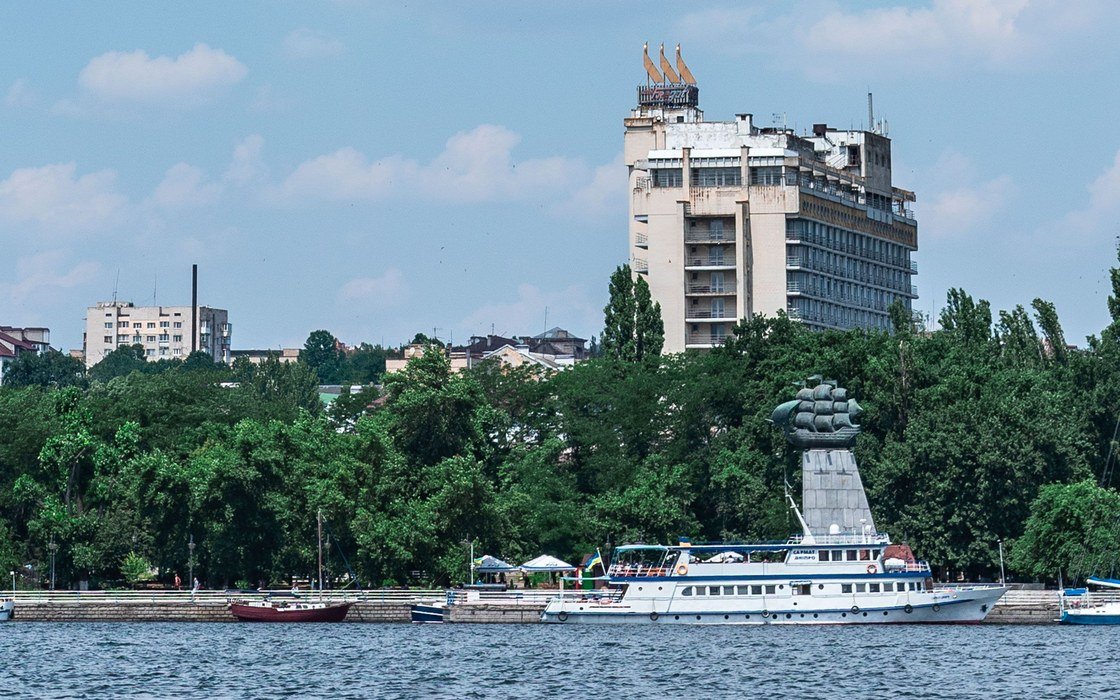The waterfront at Kherson on the Dnipro, with a tall building above the tree line
