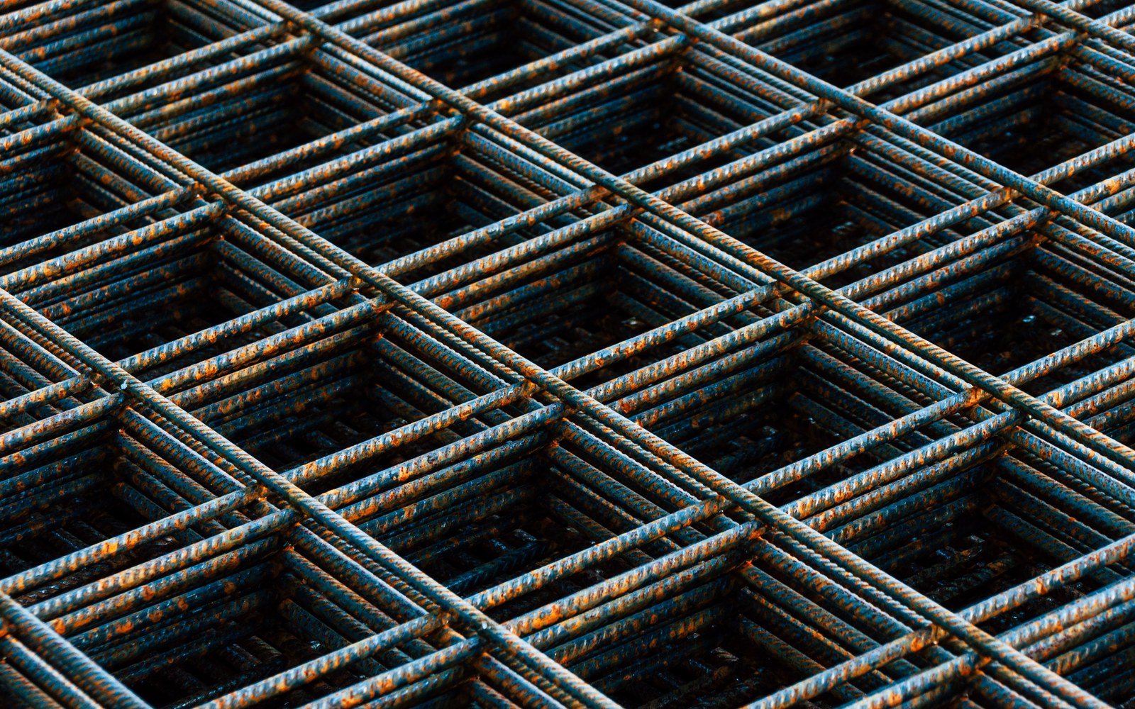 Stacked sheets of steel reinforcement mesh on a construction site, seen close and filling the frame