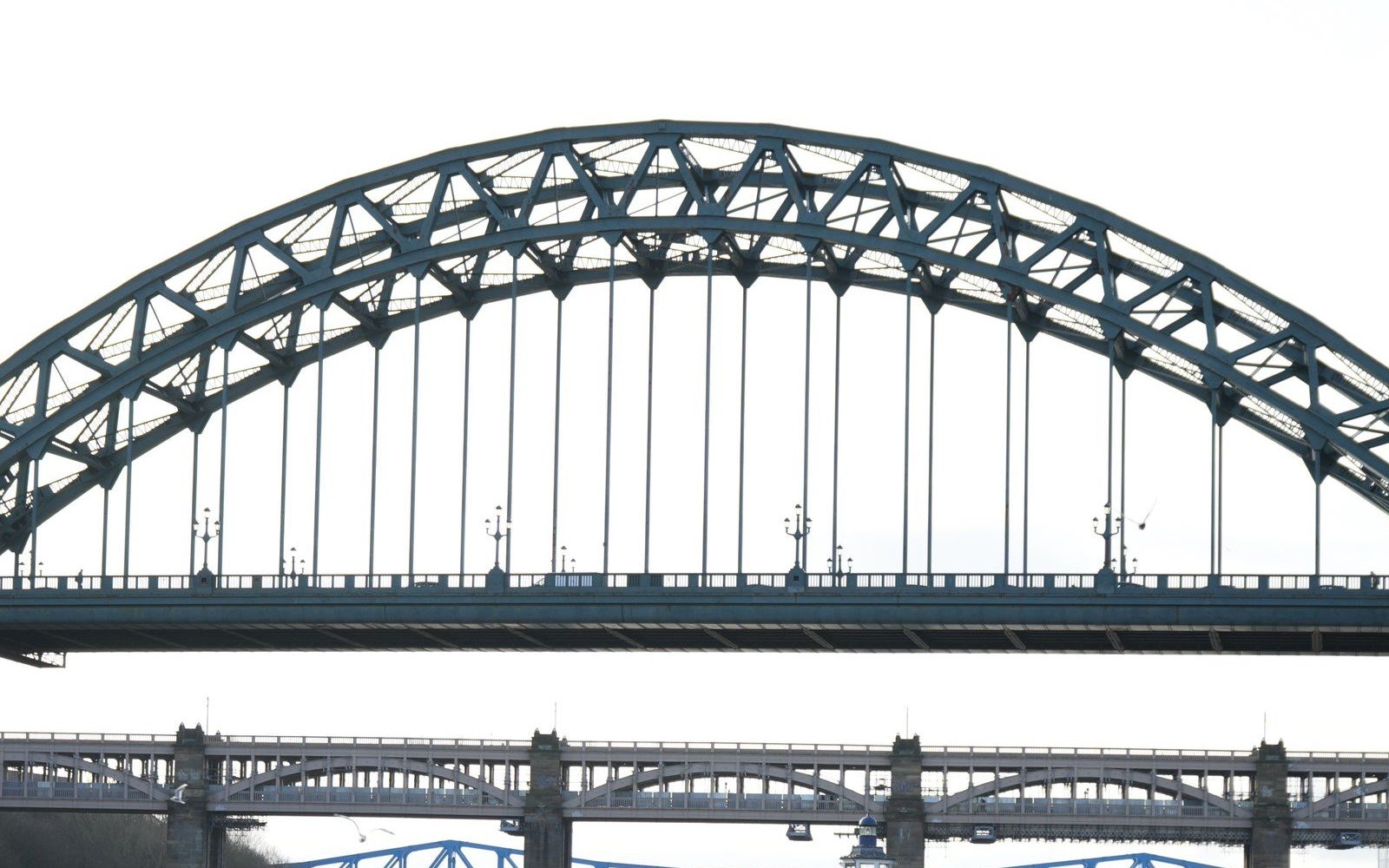 The steel arch of the Tyne Bridge spanning the River Tyne with the High Level Bridge crossing behind it