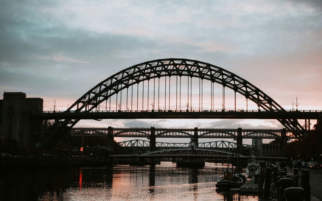 The steel arch of the Tyne Bridge over the river at dusk