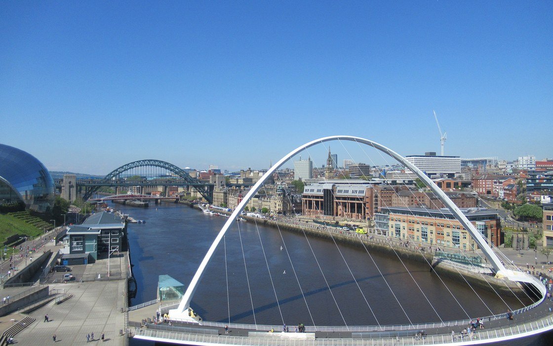 The Gateshead Millennium Bridge arching over the River Tyne, with the Newcastle quayside and further bridges beyond