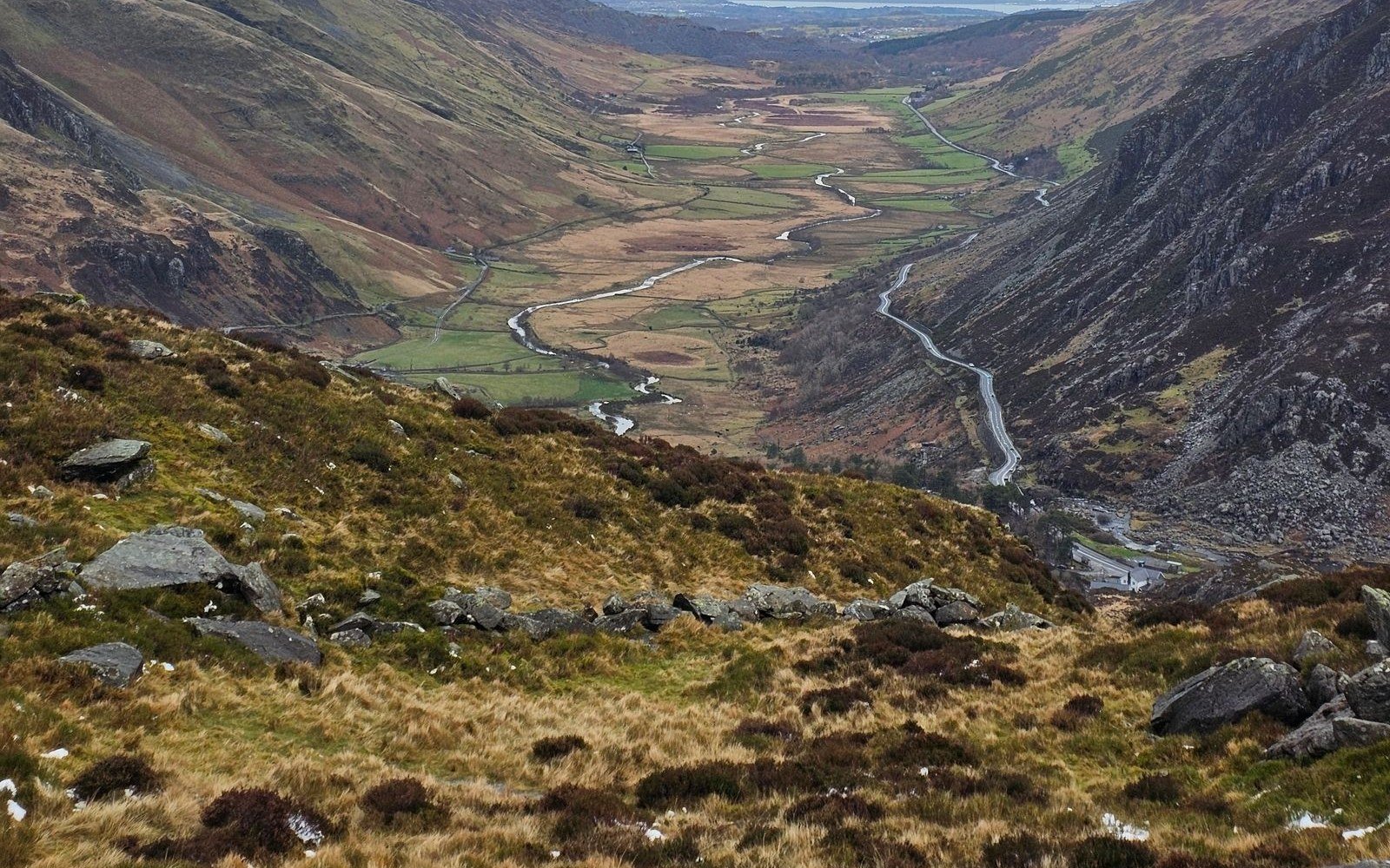 A road threading along the floor of a steep sided Welsh valley, with rough moorland in the foreground and fields beyond