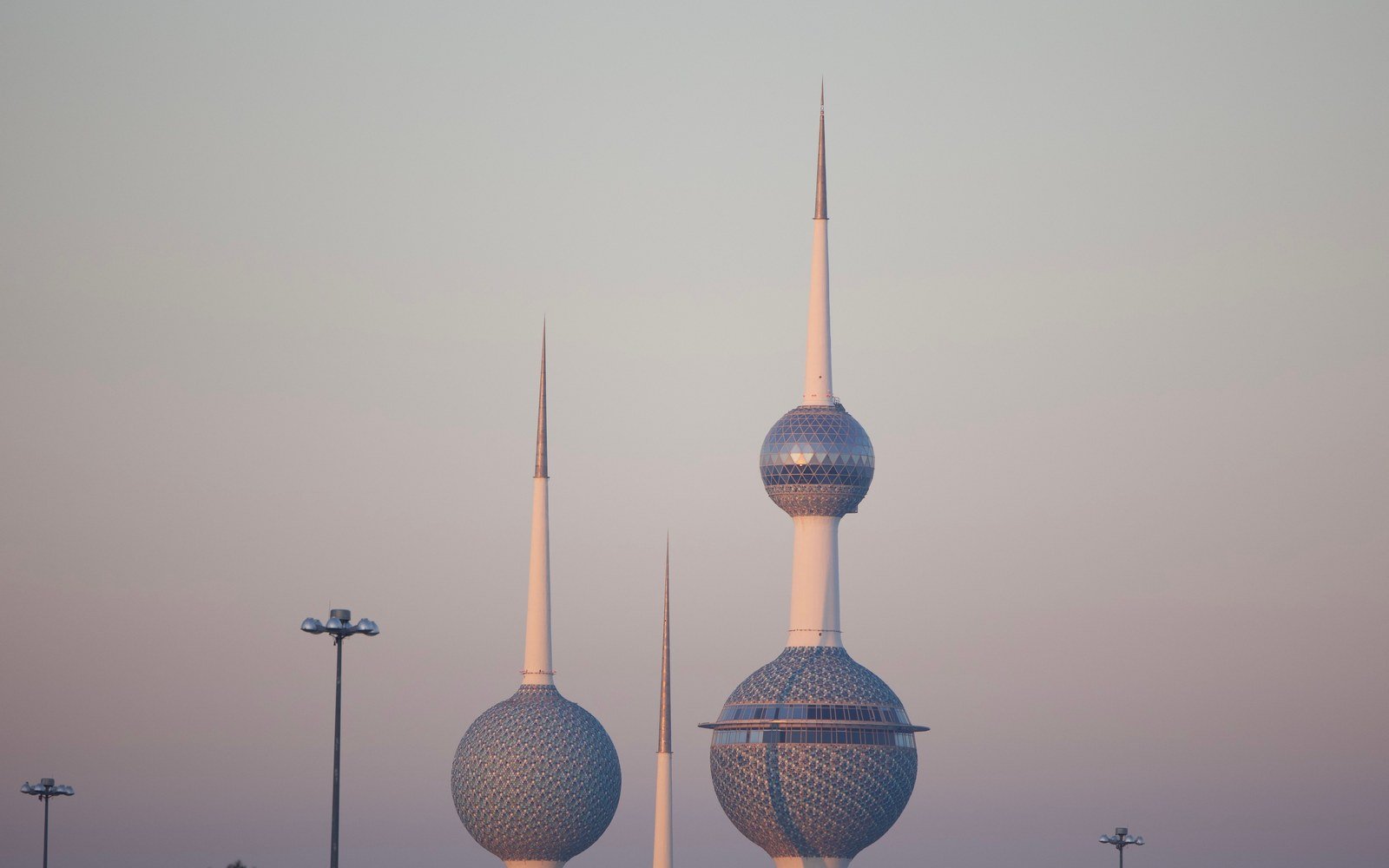 The three towers of the Kuwait Towers landmark in Kuwait City at dusk, their tiled spheres catching the last light