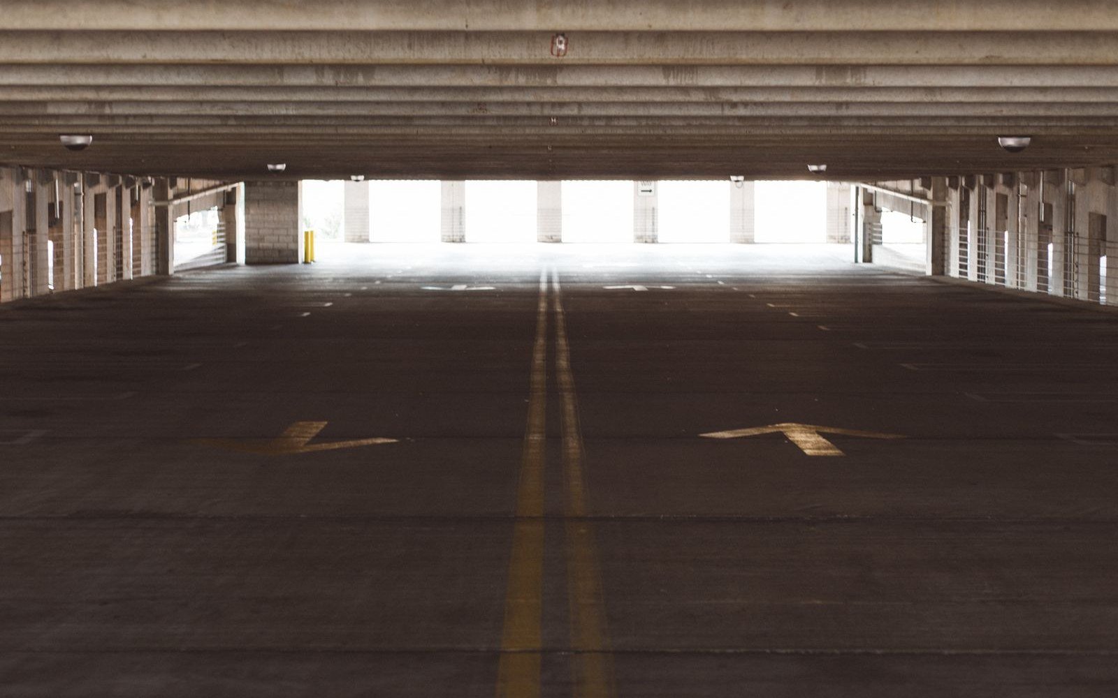 Empty concrete deck of a multi storey car park with directional arrows painted on the floor