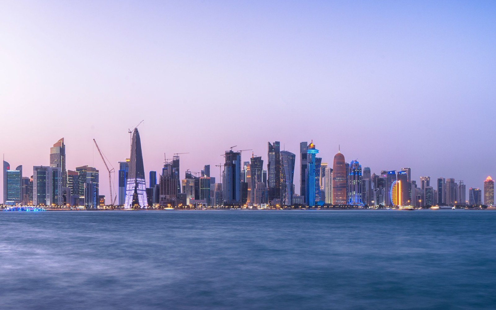 Towers and construction cranes along the Doha waterfront at dusk