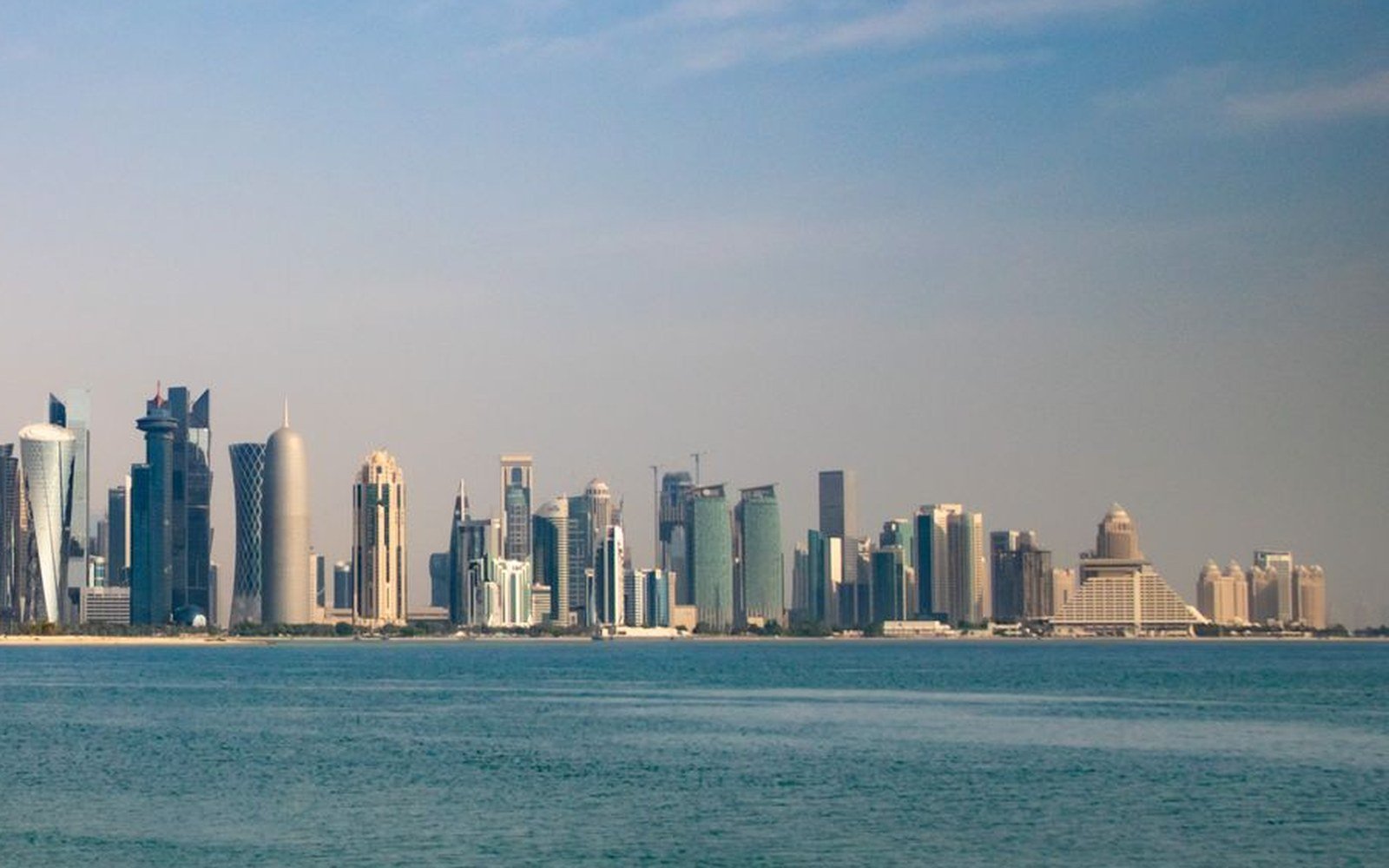 The Doha skyline seen across the water from the Corniche under a clear sky