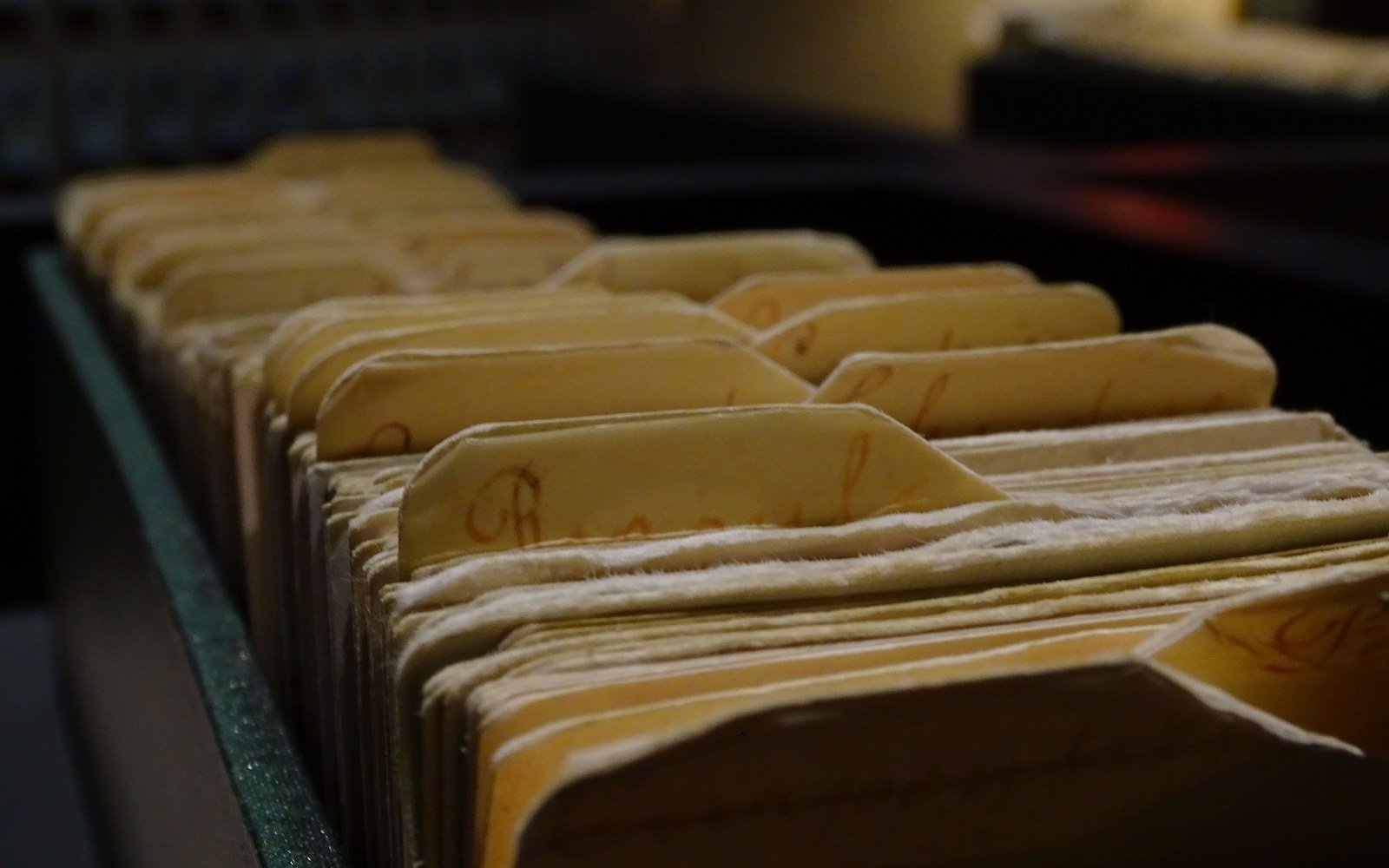 A drawer of index cards with handwritten dividers, photographed close up in low light