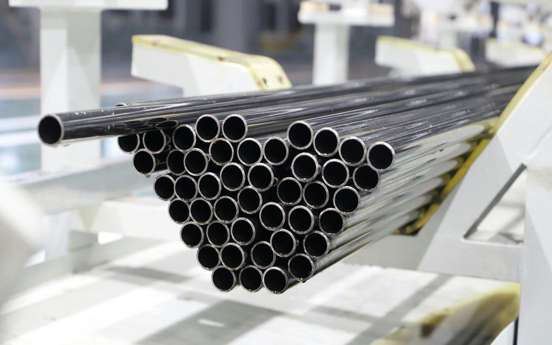 A bundle of new steel tubes stacked on a rack in a manufacturing plant