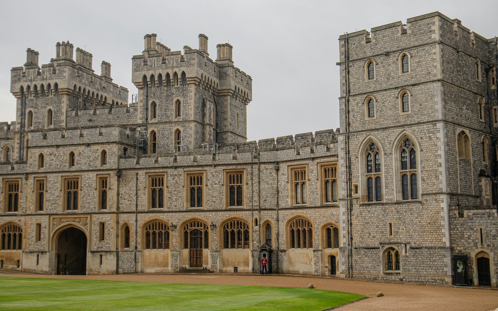 The stone ranges and towers of Windsor Castle seen across the lawn of the quadrangle, with no people in frame