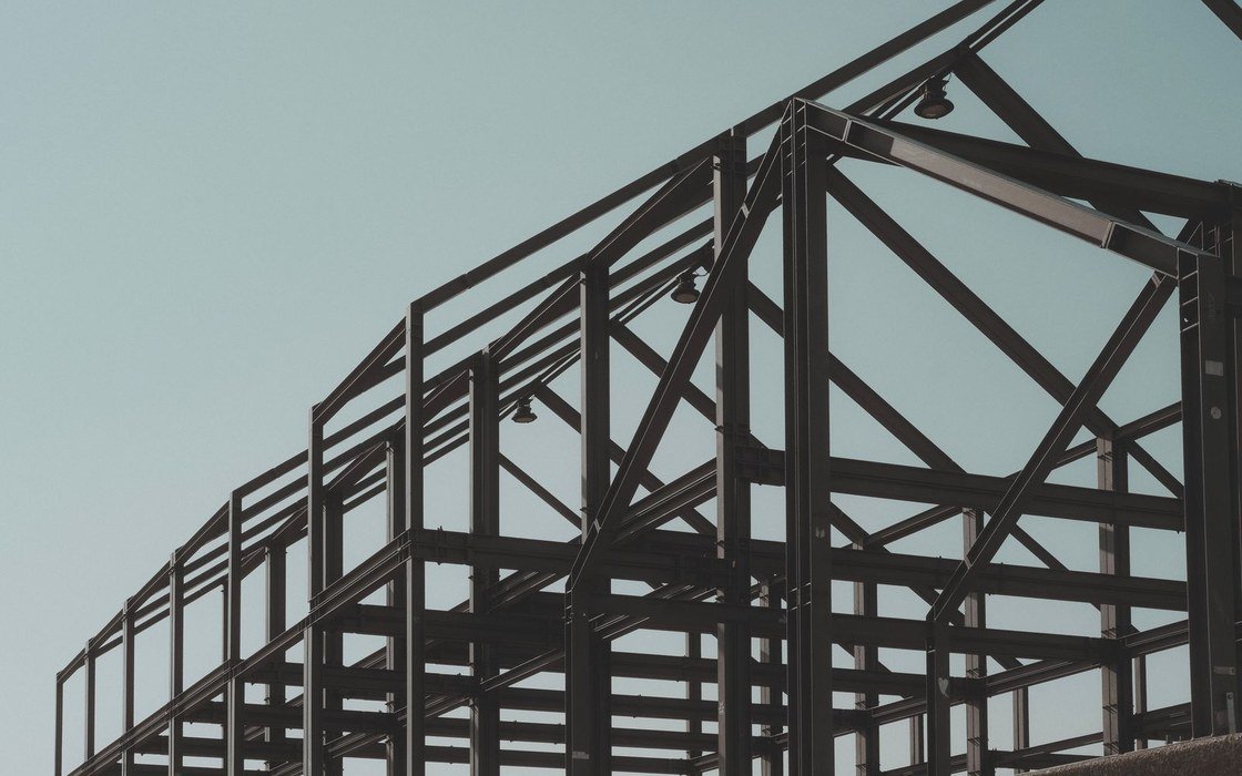 A structural steel frame rising against a clear pale sky