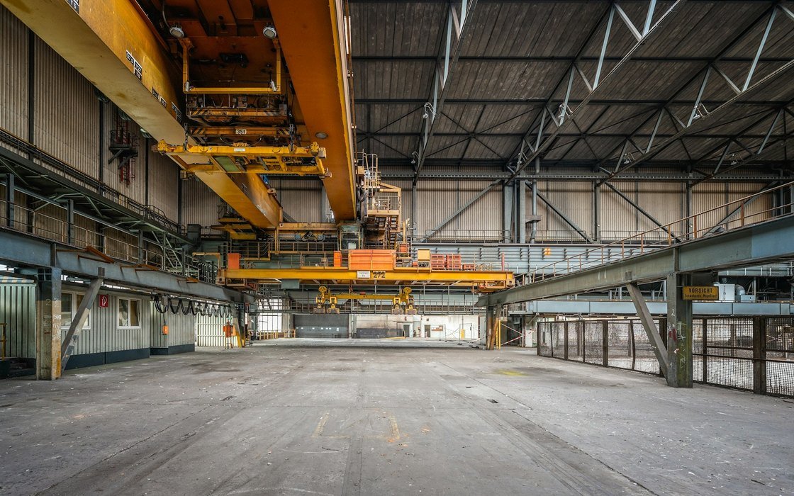 Yellow overhead travelling cranes on runway beams inside a large industrial hall