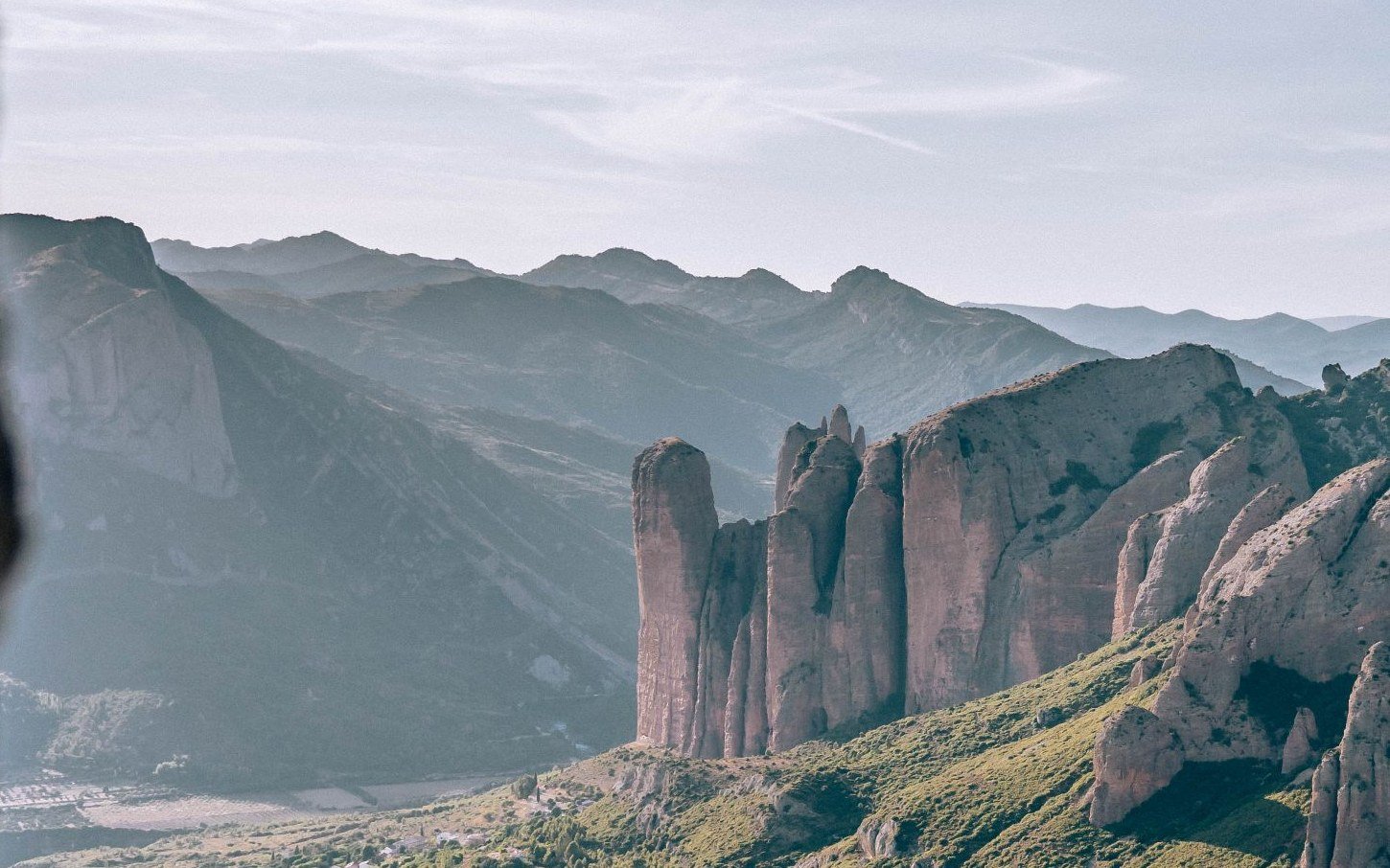 The rock towers of the Mallos de Riglos above a green valley in Huesca, Aragon