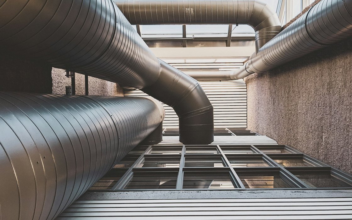 Large spiral ventilation ductwork running across a ceiling void above steel framing inside a building under fit out