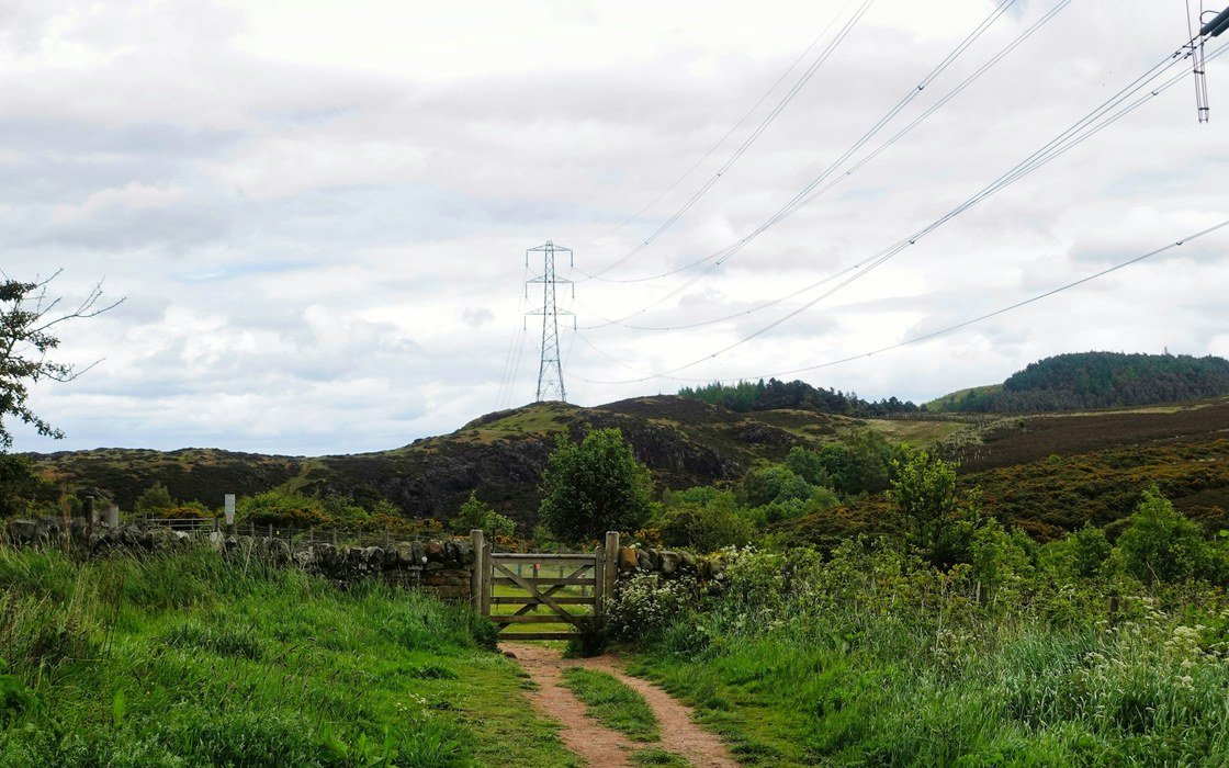 A transmission pylon and overhead lines above rough hill ground in Scotland