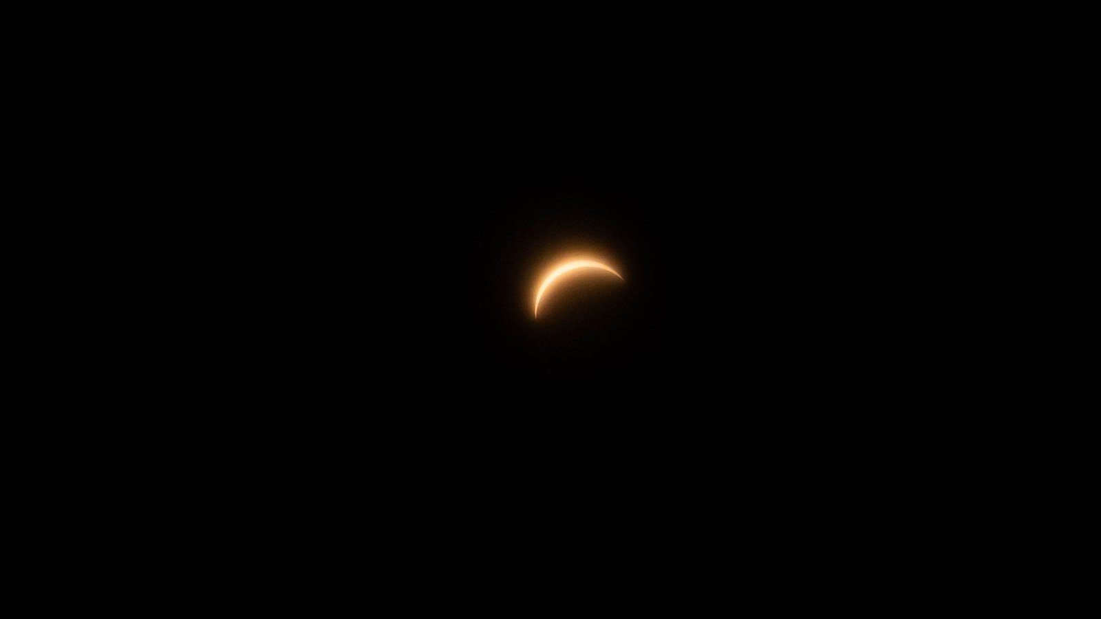 A solar eclipse in partial phase, the sun reduced to a bright crescent against a dark sky