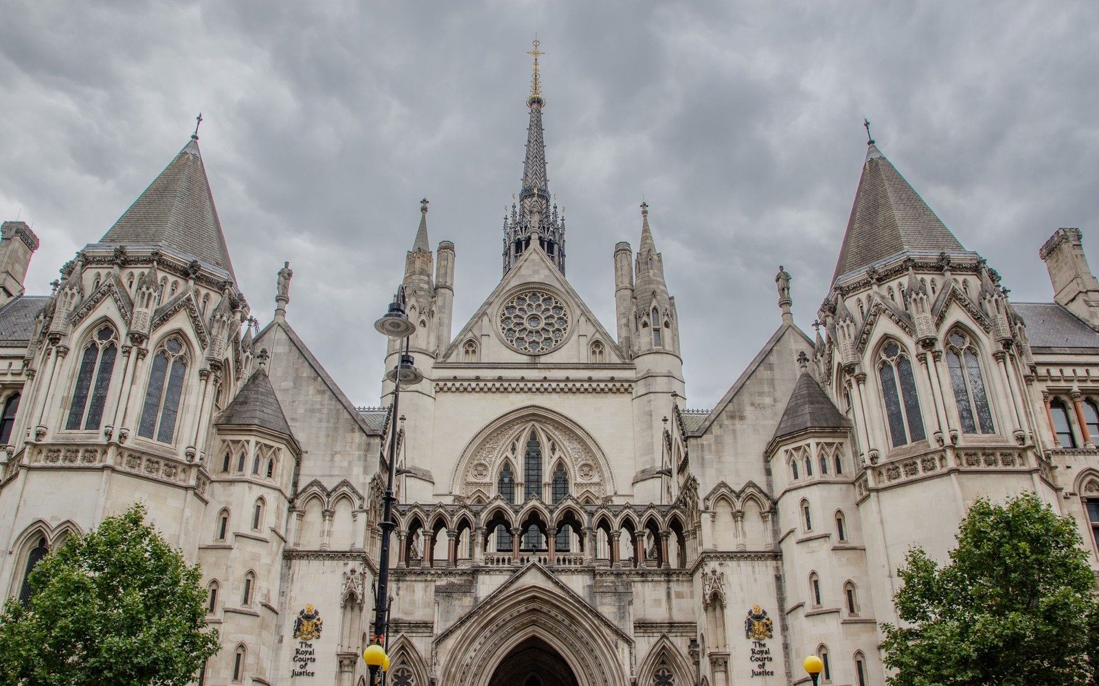 The Gothic stone frontage, twin spires and rose window of the Royal Courts of Justice under a grey sky